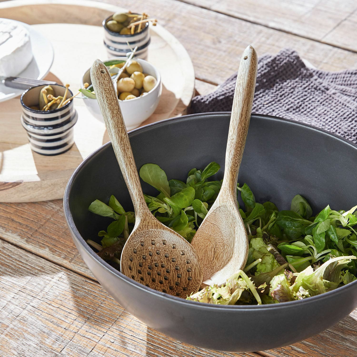 Couverts à salade Helier Saladier noir en bois avec salade verte et cuillères en bois sur table en bois rustique