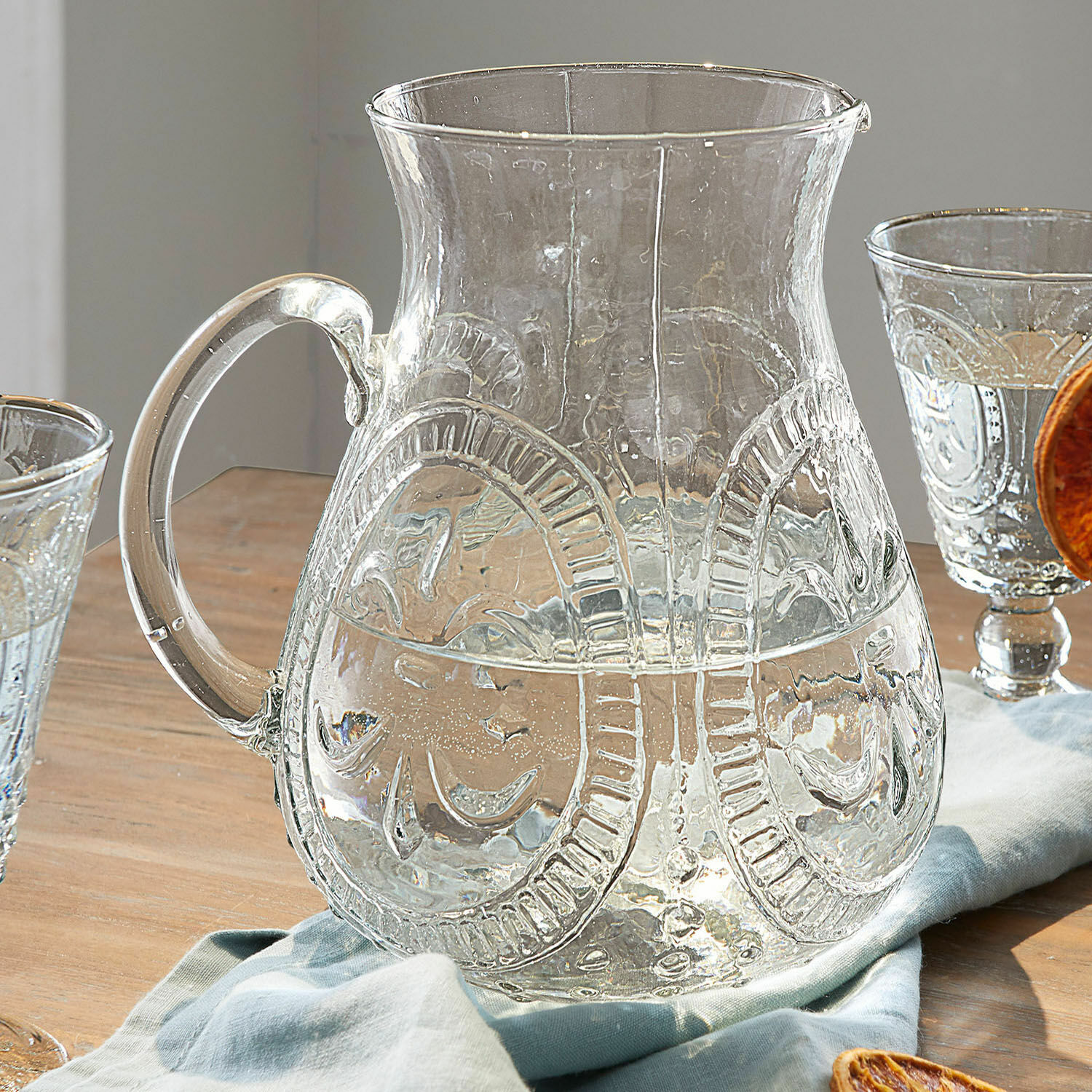 Pichet Pépin Carafe en verre transparent avec motif décoratif sur table en bois avec serviette