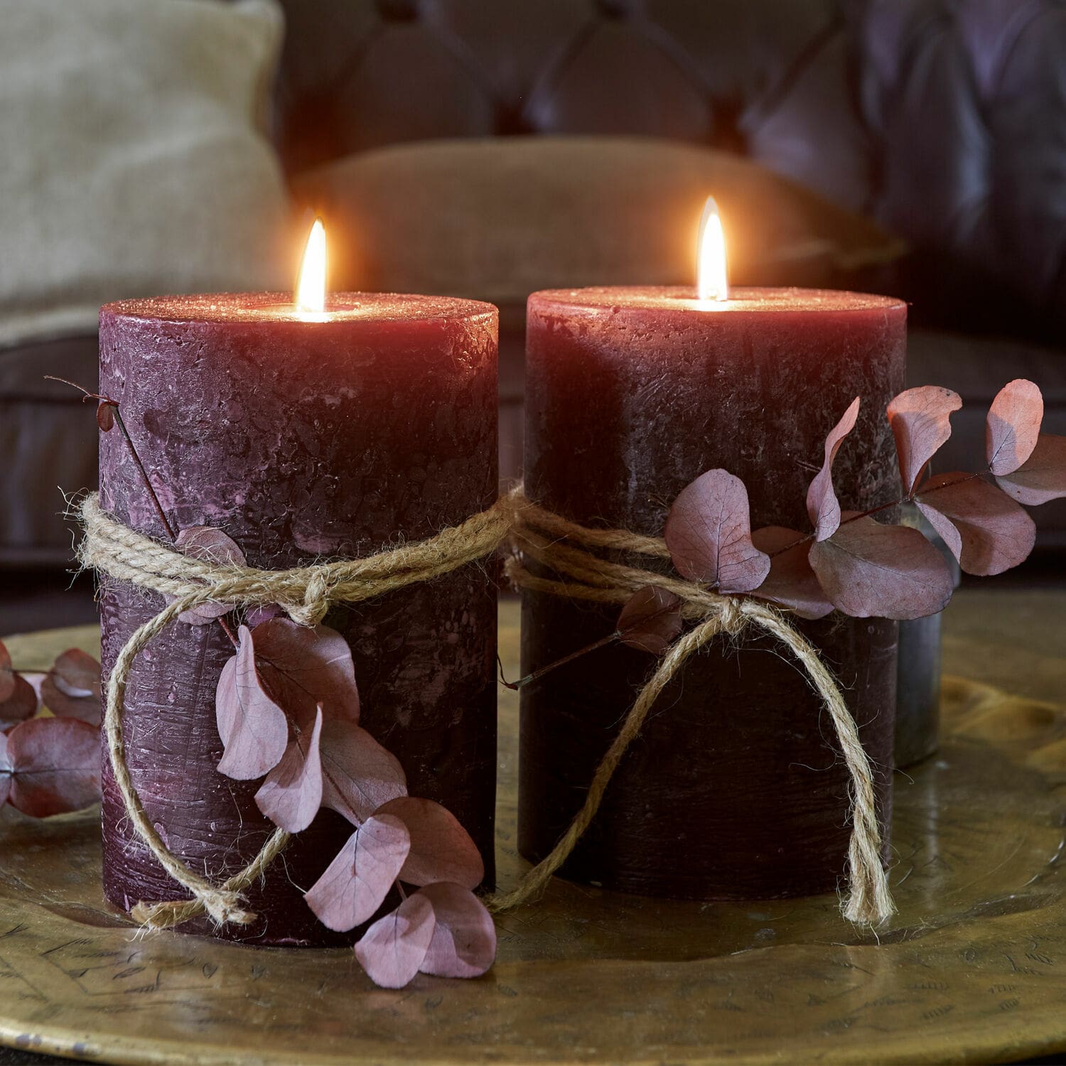 Lot de 2 bougies Oviedo Deux bougies bordeaux avec corde naturelle et feuilles séchées sur un plateau en laiton décoratif