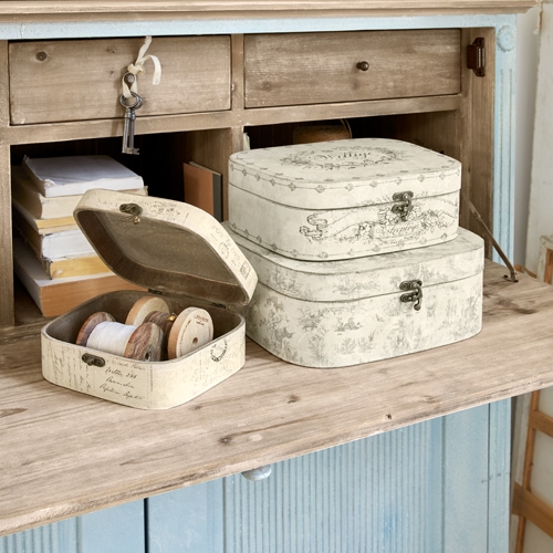 Ensemble de trois boîtes décoratives crème à motif vintage sur un plan de travail en bois, rangement pratique