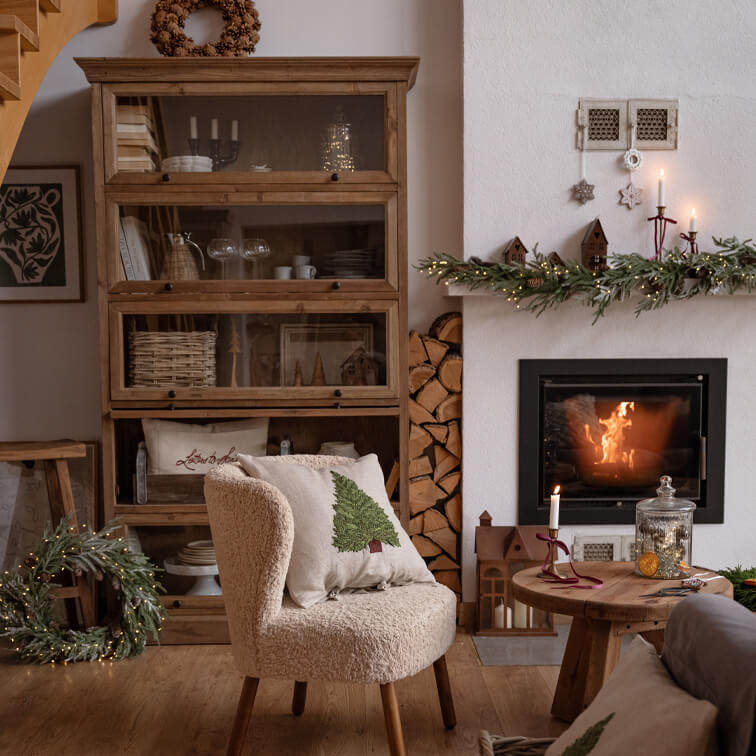 Salon chaleureux avec fauteuil crème, meuble en bois et cheminée décorée pour Noël