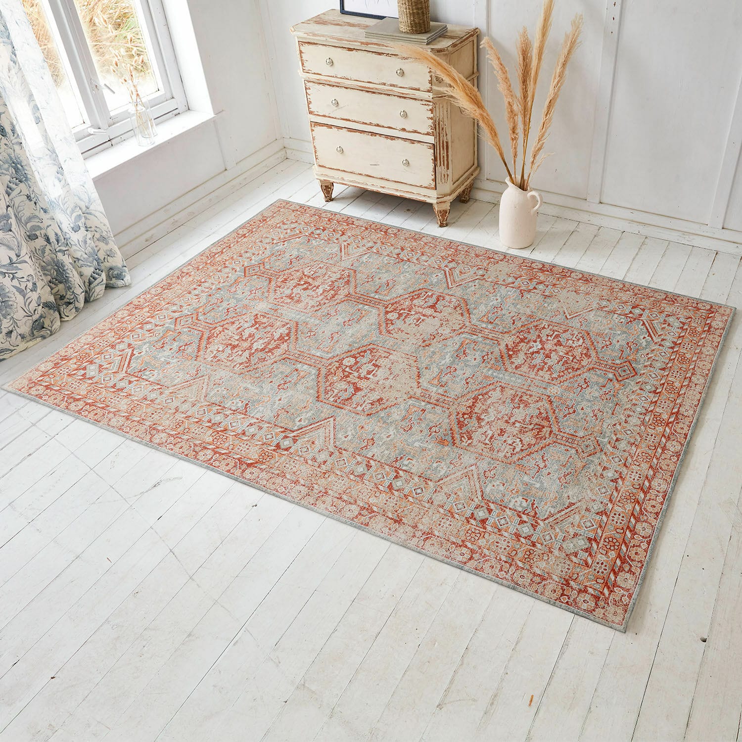 Tapis Incantaro Tapis à motif rouille et bleu clair sur un sol clair dans une pièce lumineuse avec commode