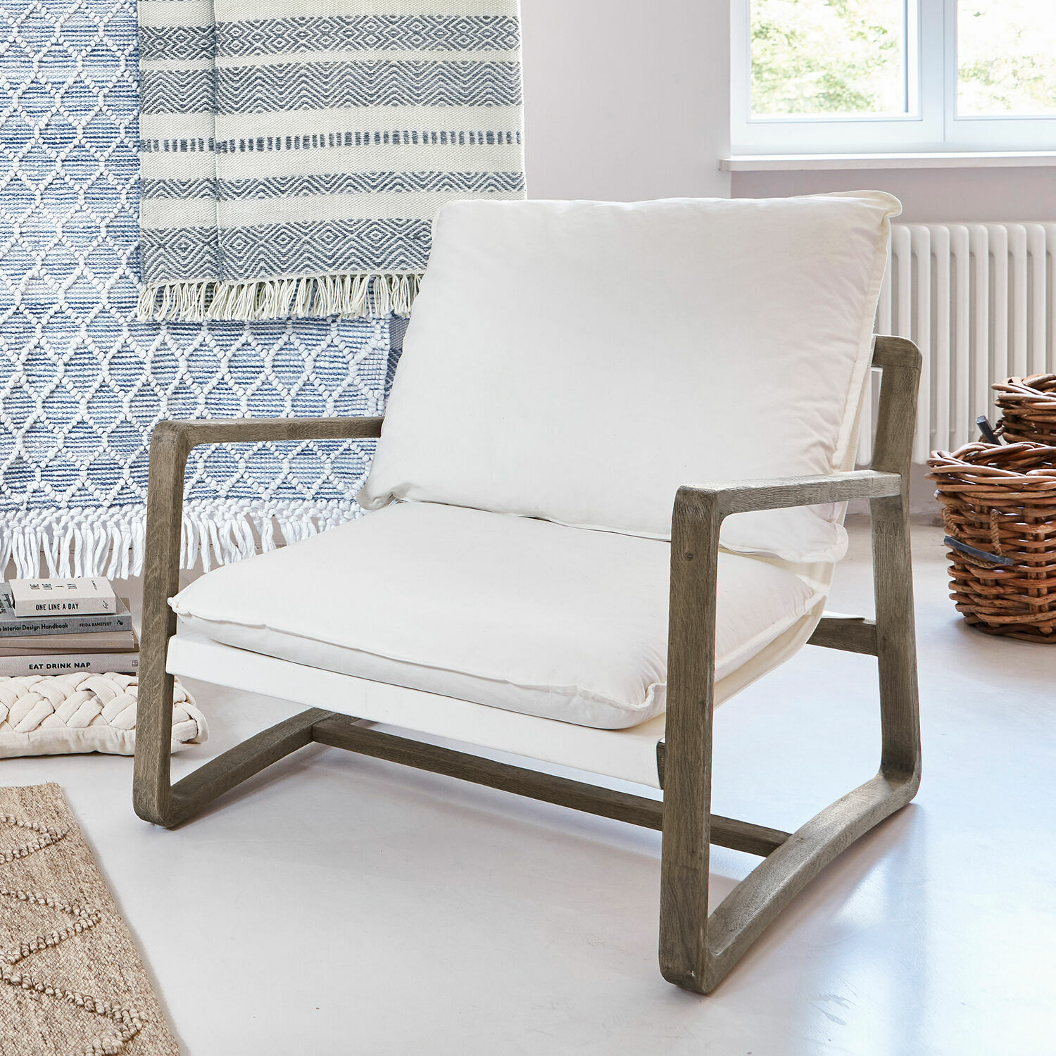 Fauteuil Jowna Fauteuil avec cadre en bois et coussin en coton blanc dans un intérieur lumineux et moderne