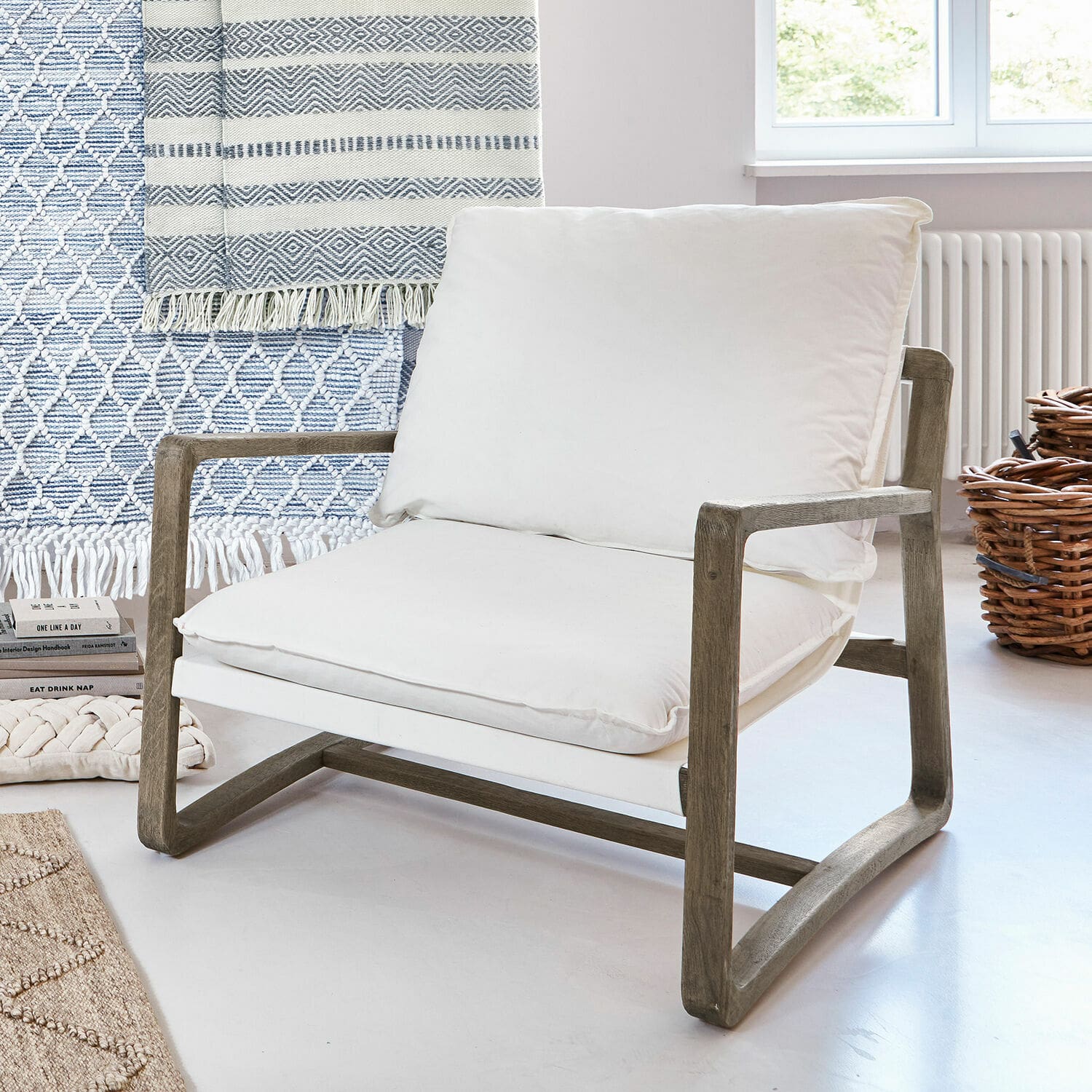 Fauteuil Jowna Fauteuil avec cadre en bois et coussin en coton blanc dans un intérieur lumineux et moderne
