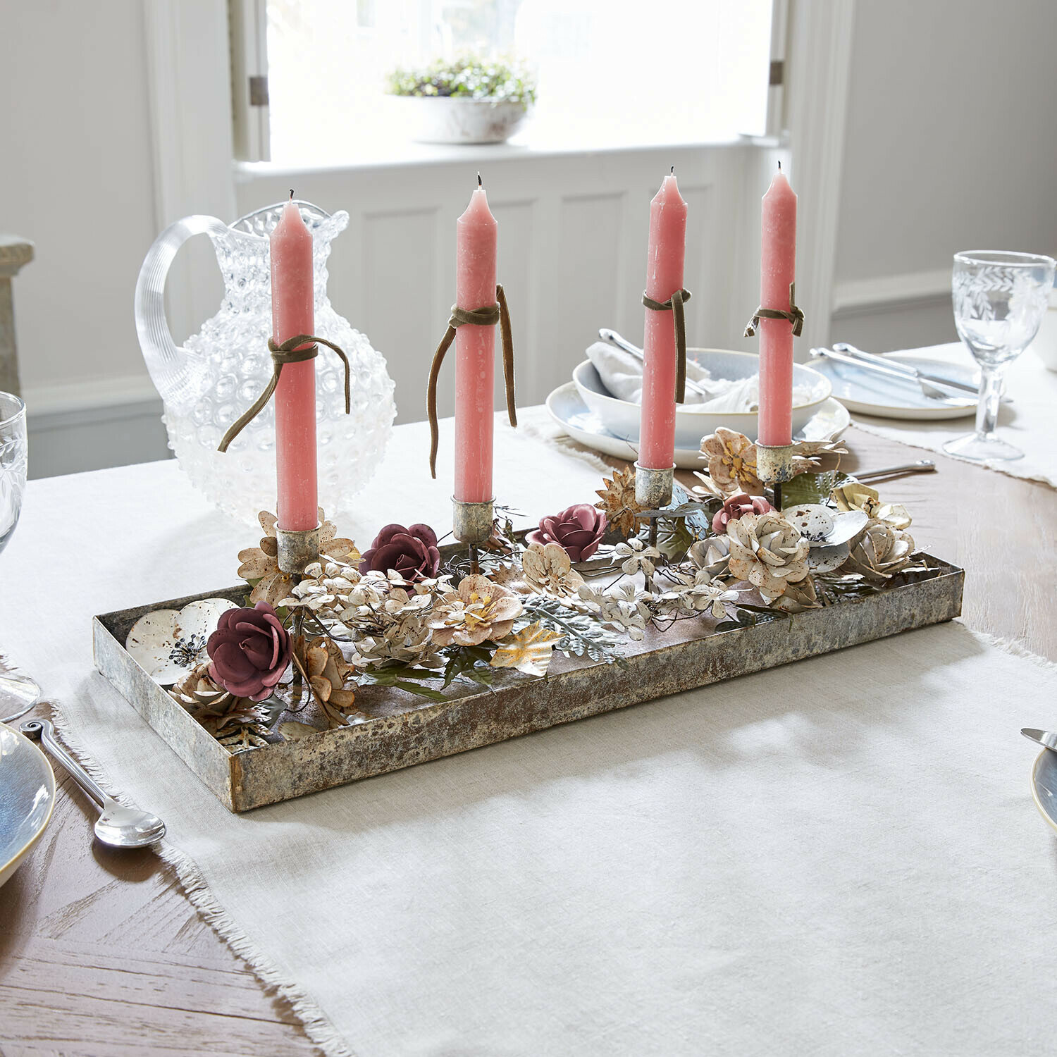 Plateau à bougies Duvérine Bougeoir en métal avec quatre bougies roses et décor floral sur une table de salle à manger