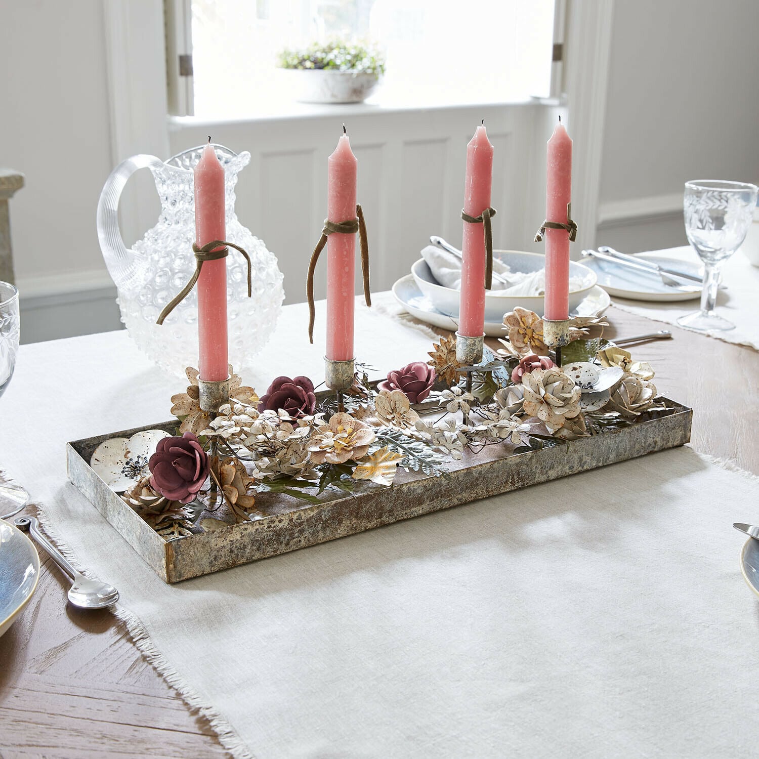 Plateau à bougies Duvérine Bougeoir en métal avec quatre bougies roses et décor floral sur une table de salle à manger