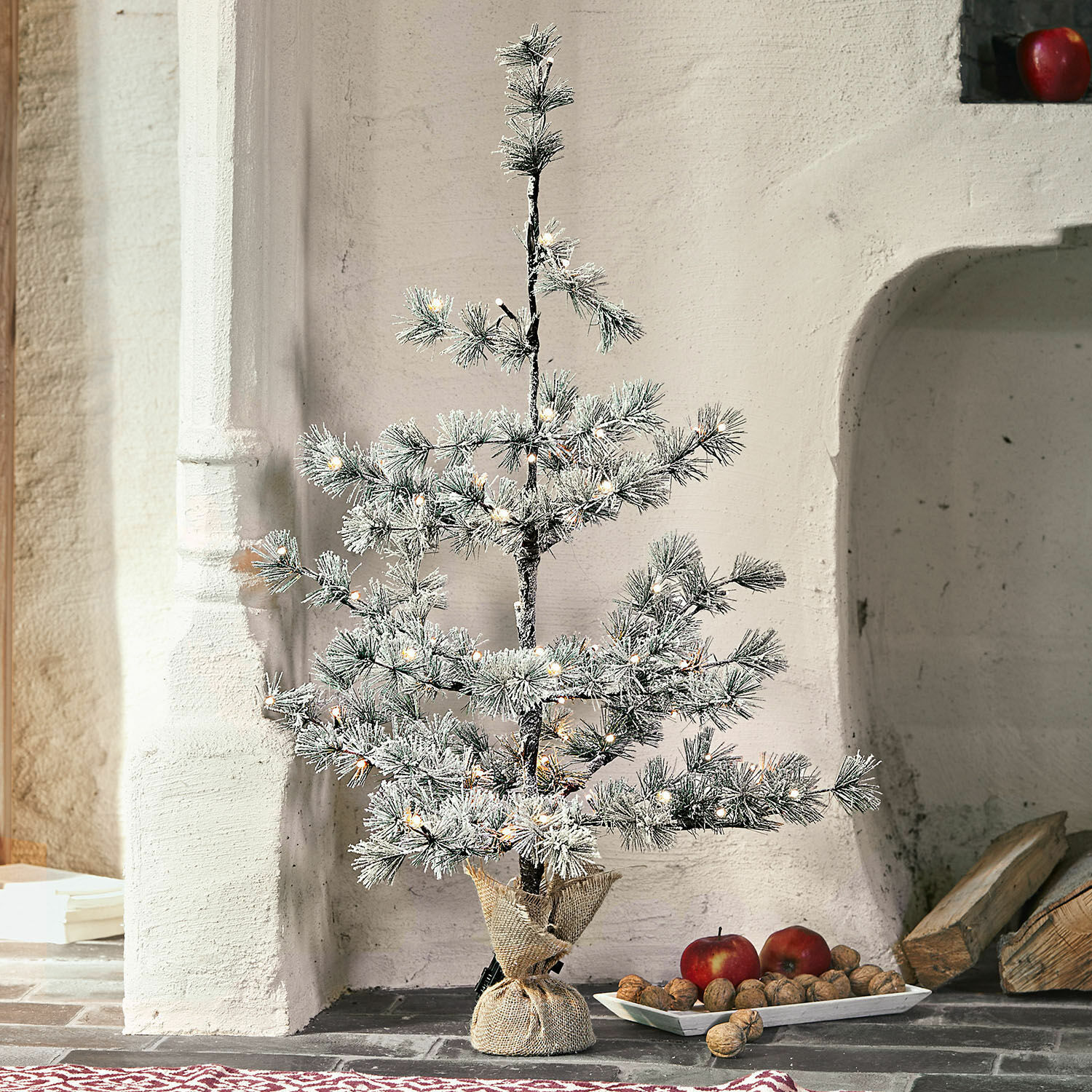 Sapin de Noël Falkirk Petit sapin artificiel avec branches enneigées et lumières LED dans un sac en jute posé au sol