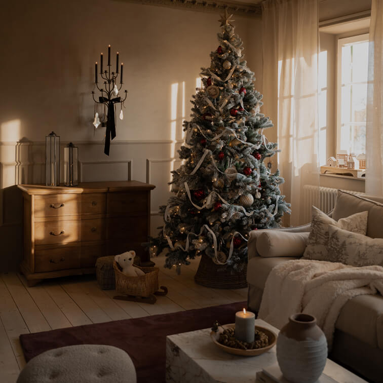 Salon chaleureux avec sapin de Noël décoré, commode en bois et chandelier mural allumé