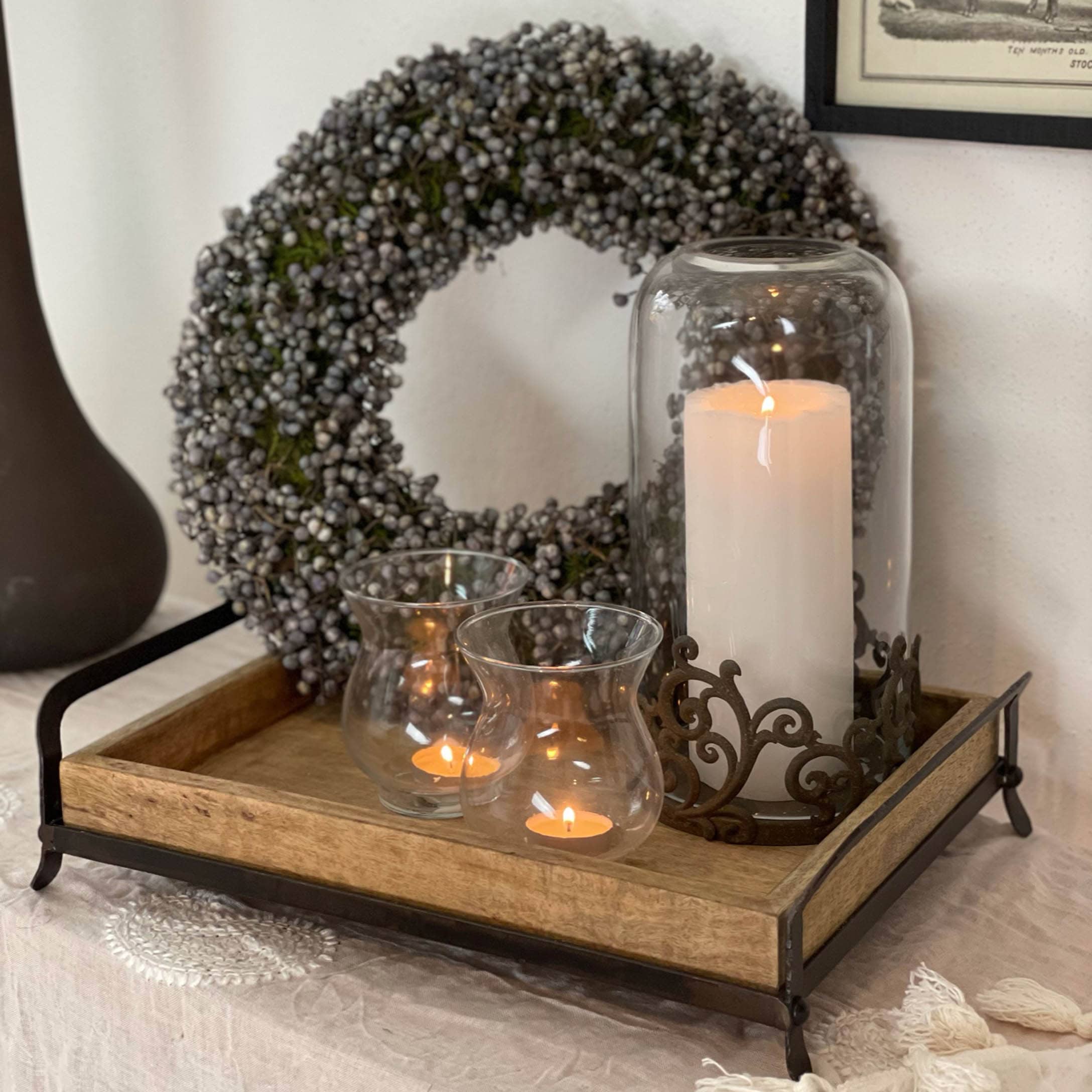 Plateau en bois avec cadre en métal, bougies décoratives et couronne d'automne aux baies grises