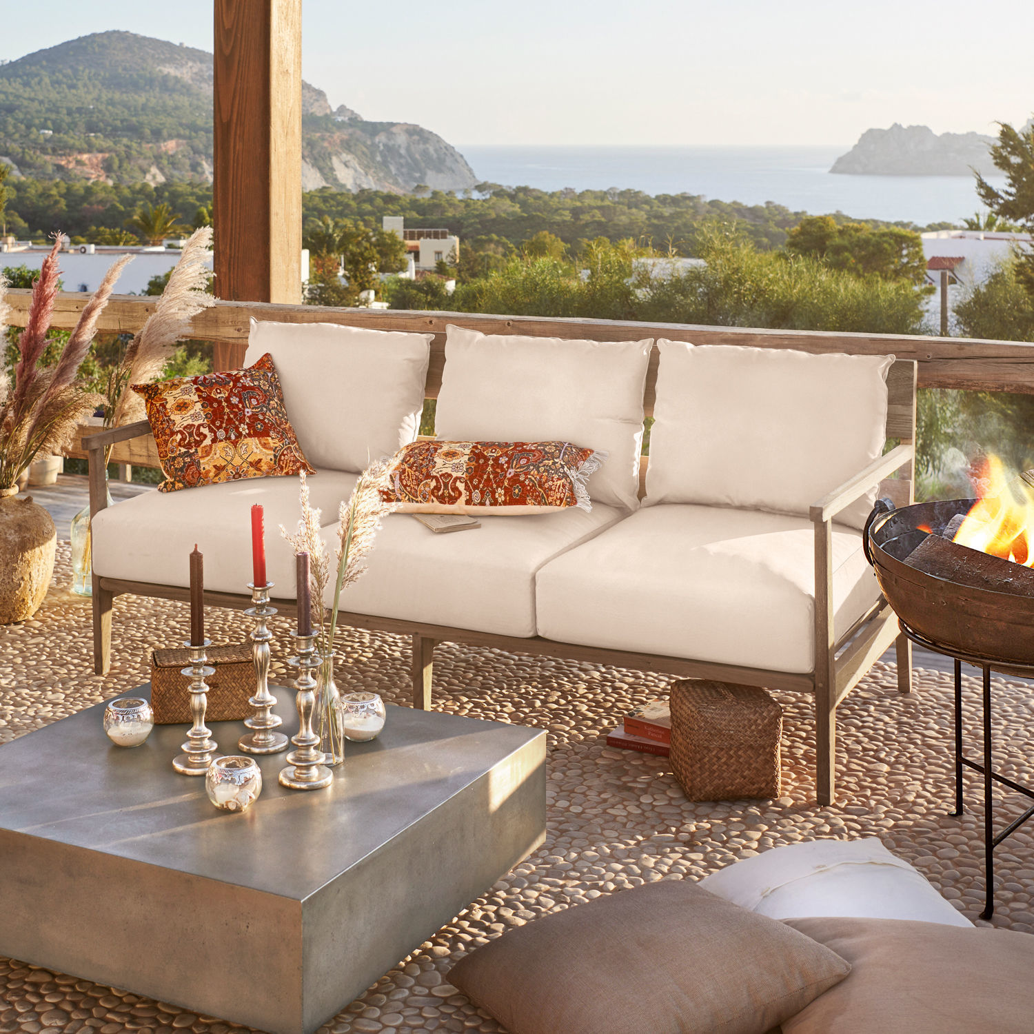 Canapé Kingsbridge Canapé d'extérieur beige en bois avec coussins colorés sur terrasse avec vue sur la mer