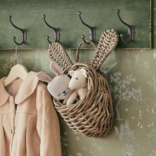 Panier en osier en forme de lapin avec oreilles, accroché à un crochet, contenant des peluches