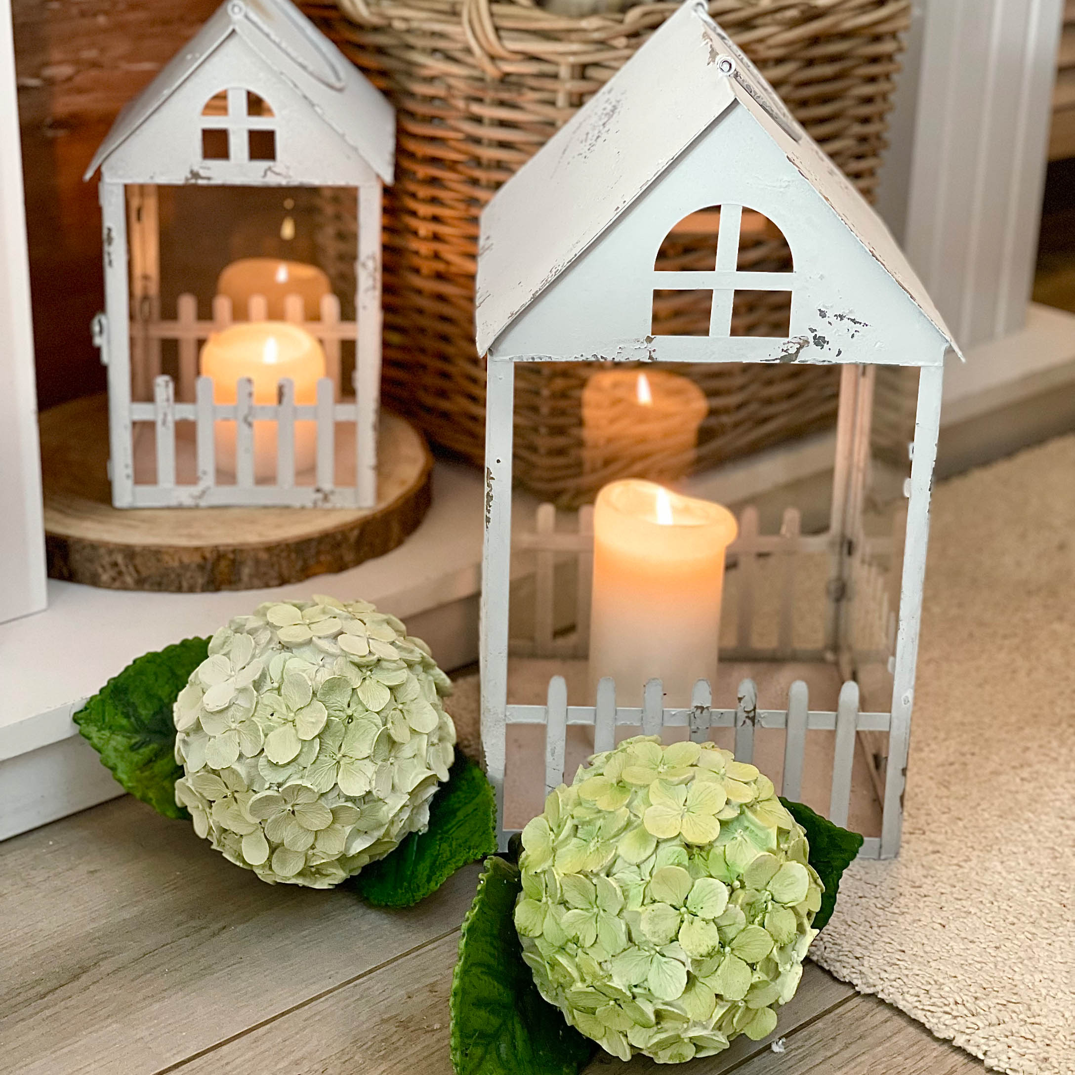 Lanterne en métal blanc style rustique avec bougies allumées et décoration florale verte