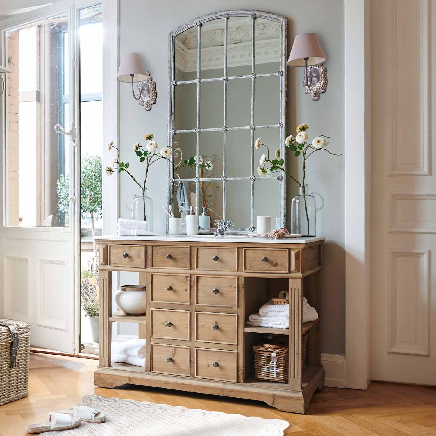 Commode en bois naturel avec plusieurs tiroirs et grand miroir vintage dans une pièce lumineuse