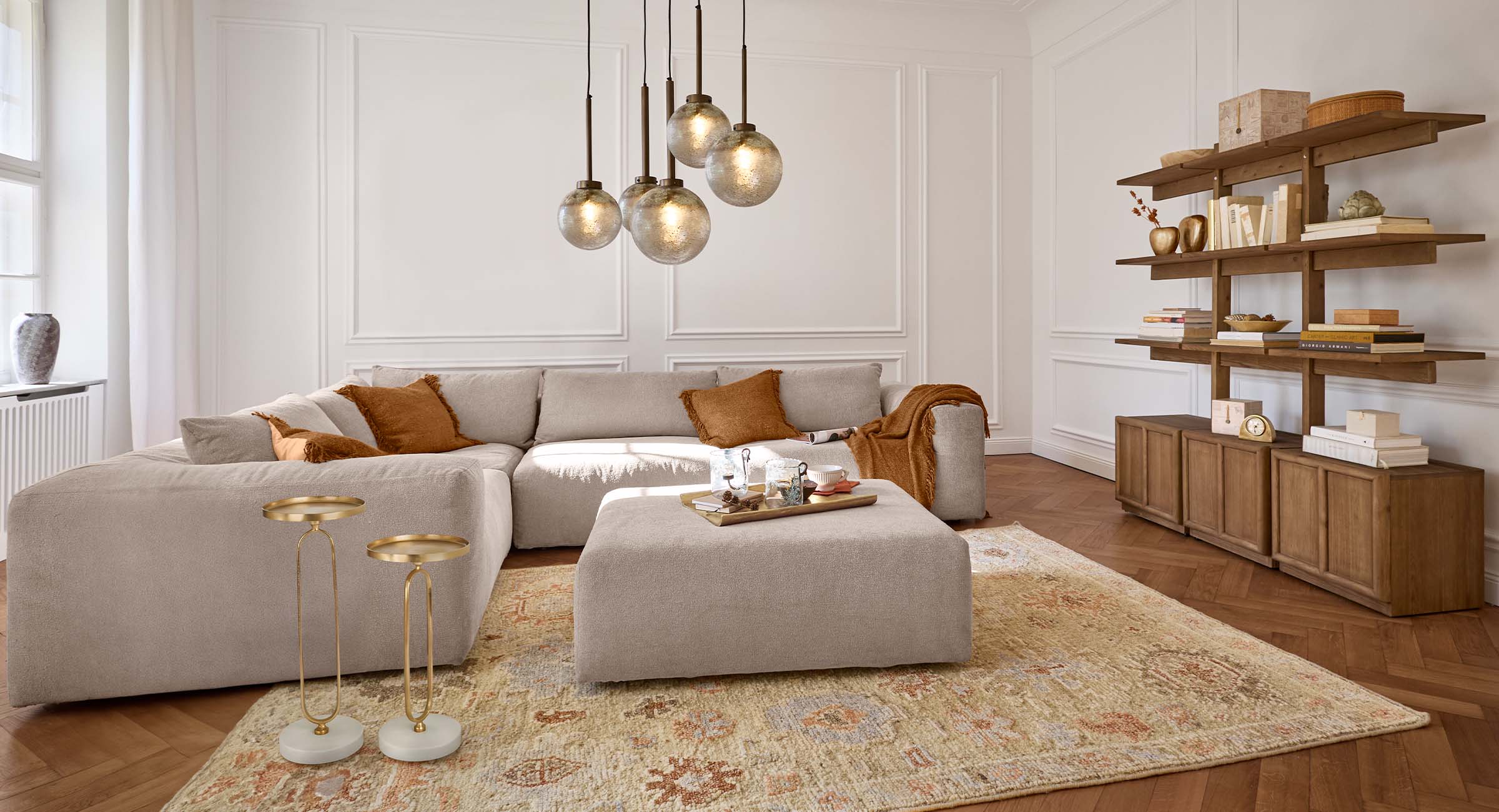Salon chaleureux avec canapé beige, coussins marron et étagère en bois dans des tons naturels élégants