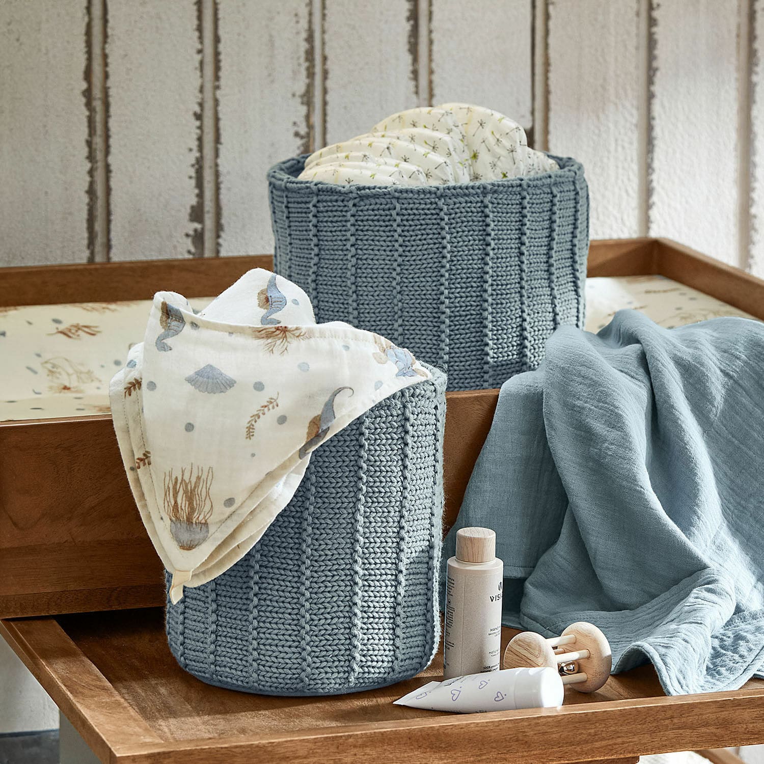 Lot de 2 paniers Fiorenzo Deux paniers tricotés bleus pour couches et accessoires bébé sur table à langer en bois