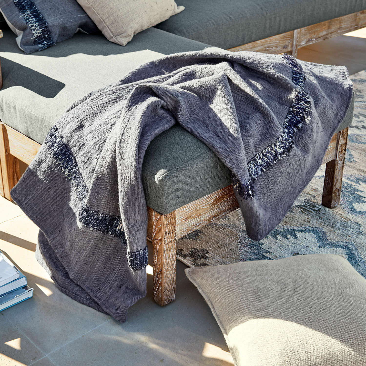 Plaid Foix Plaid gris en coton avec motif bleu marine sur banc en bois et coussin beige