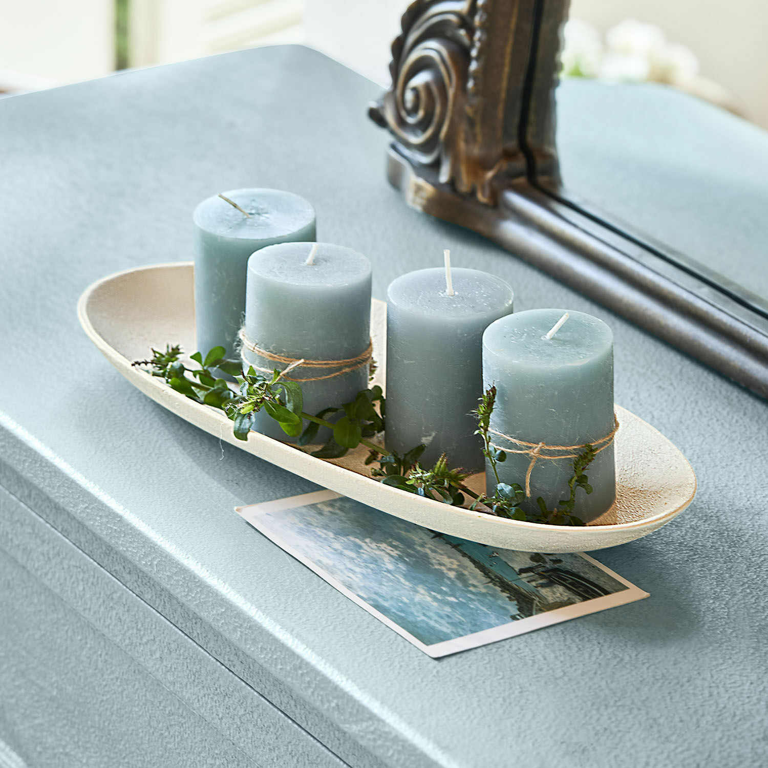 Coupelle Cantresse Ensemble de quatre bougies bleues avec décorations de feuilles vertes sur un plateau beige sur une table