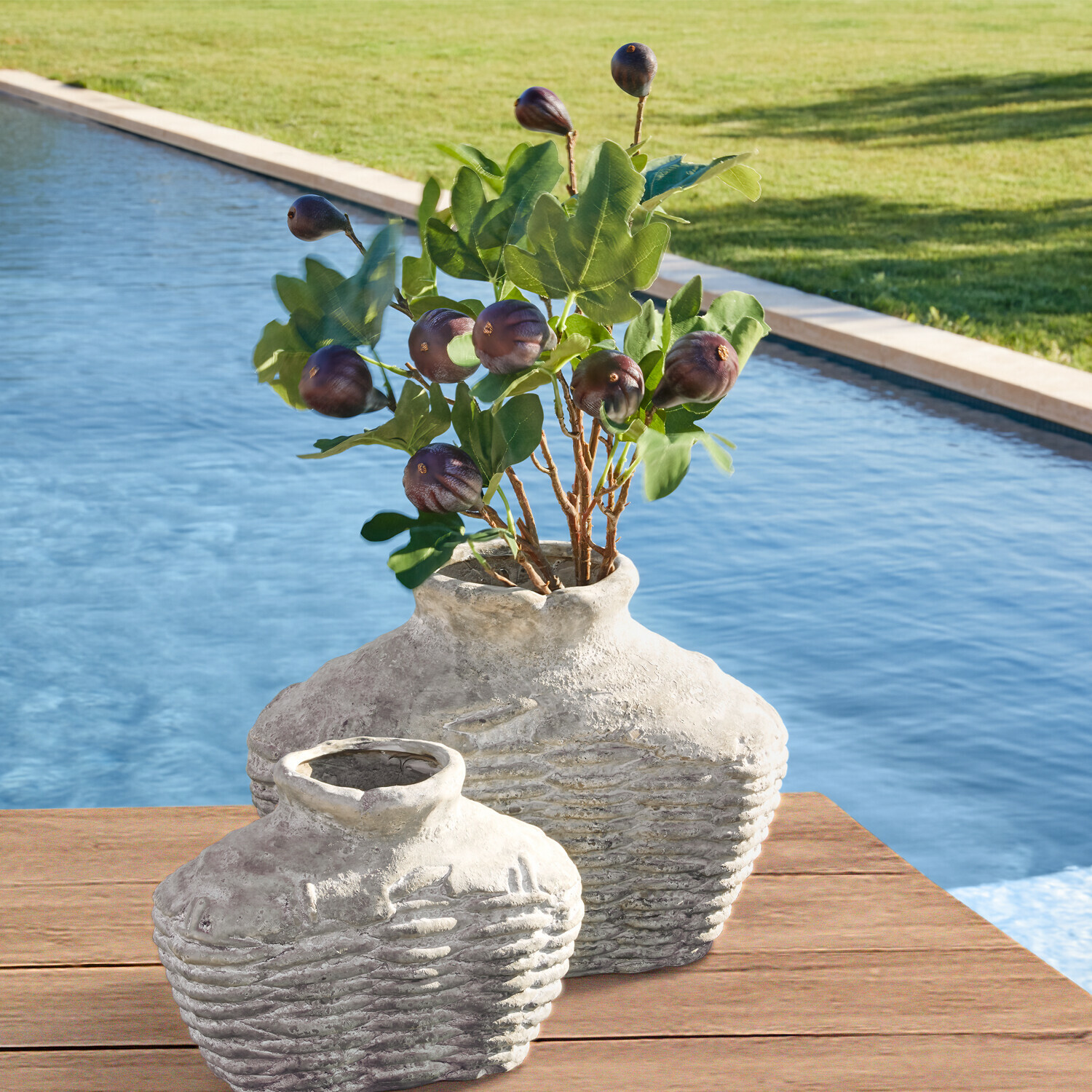 Lot de 3 tiges décoratives Alverino Deux vases rustiques en céramique grise sur une table en bois près de la piscine avec feuillage vert et fruits