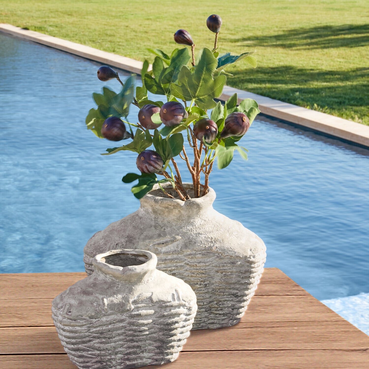Lot de 3 tiges décoratives Alverino Deux vases rustiques en céramique grise sur une table en bois près de la piscine avec feuillage vert et fruits