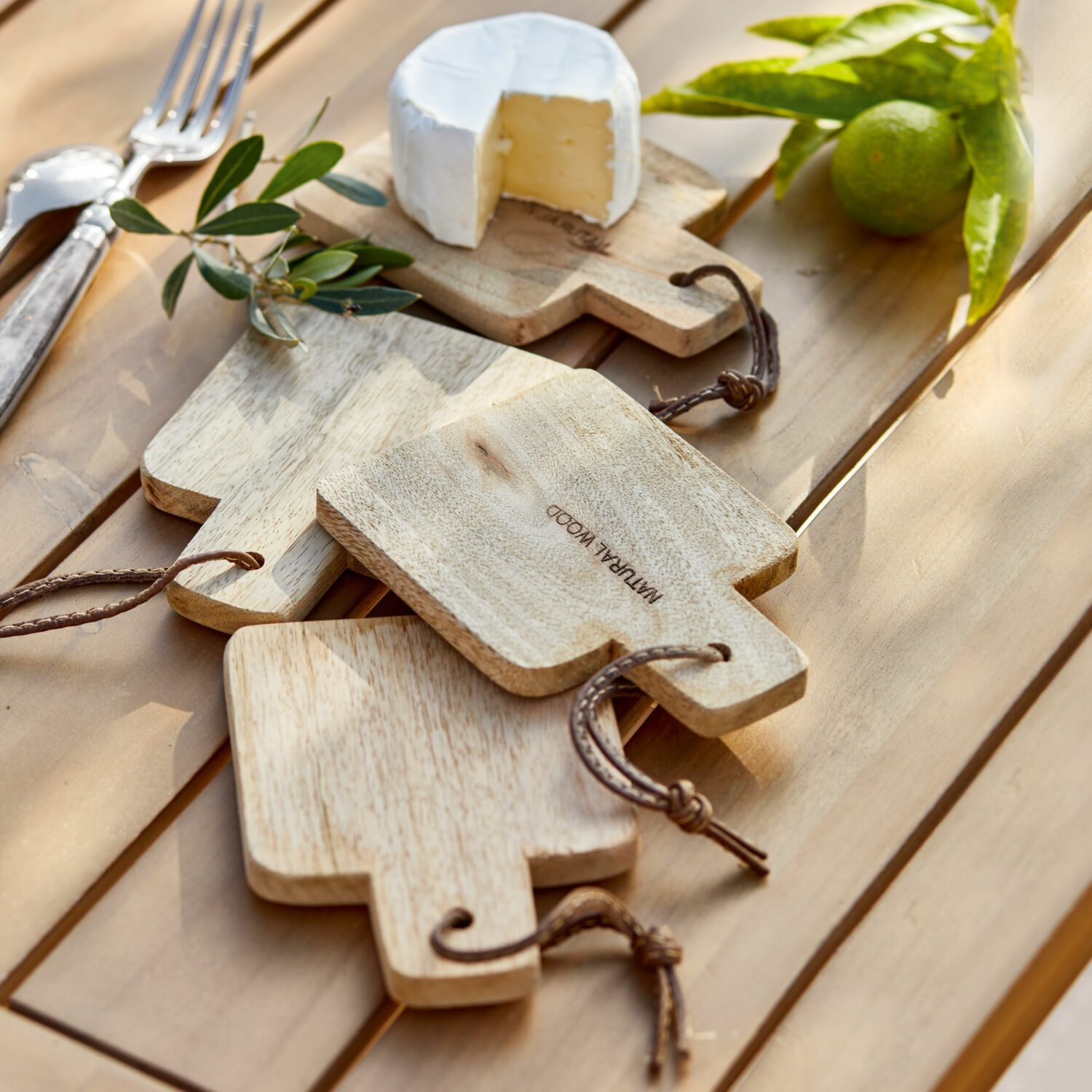 Lot de 4 planches à découper Boise Ensemble de planches à découper en bois naturel avec poignées et cordons sur table avec fromage et citron vert