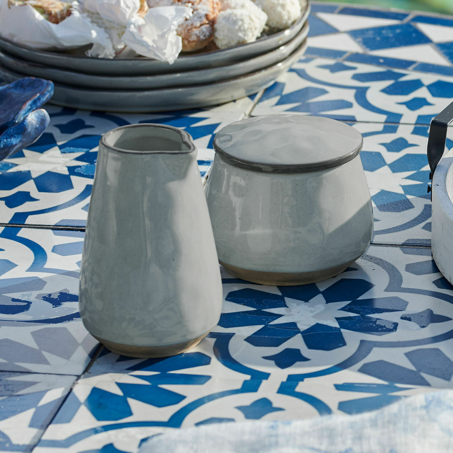 Sucrier et petit pot à lait Biarré Sucrier et pichet en céramique grise sur une table à motifs bleus et blancs pour la salle à manger