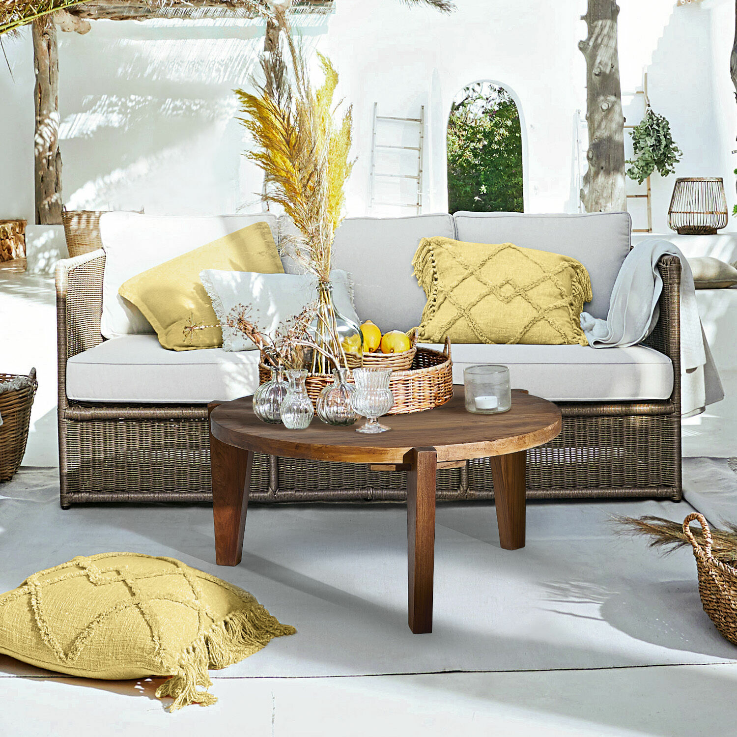 Canapé Lesmont Salon extérieur avec canapé en osier, coussins gris clair et table basse en bois sur terrasse lumineuse