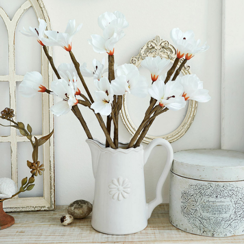 Pichet en céramique blanche avec fleurs décoratives sur table en bois, style vintage, décoration intérieure