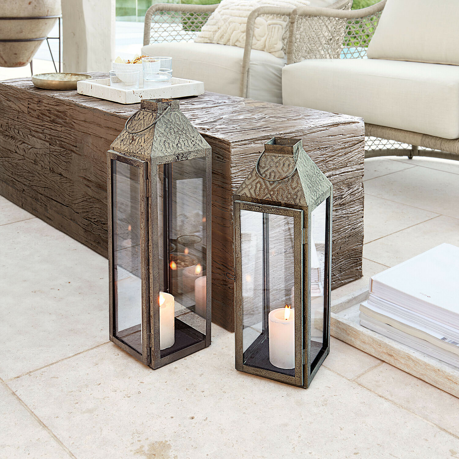 Deux lanternes en métal avec bougies blanches sur un sol clair dans un salon moderne