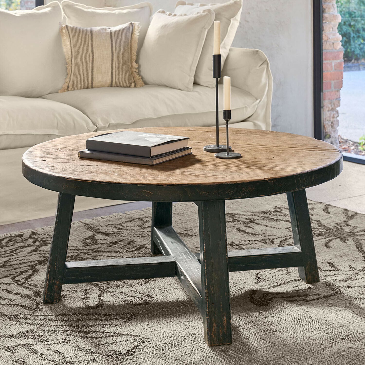 Table basse Gorivel Table basse ronde en bois naturel et noir posée sur un tapis dans un salon lumineux