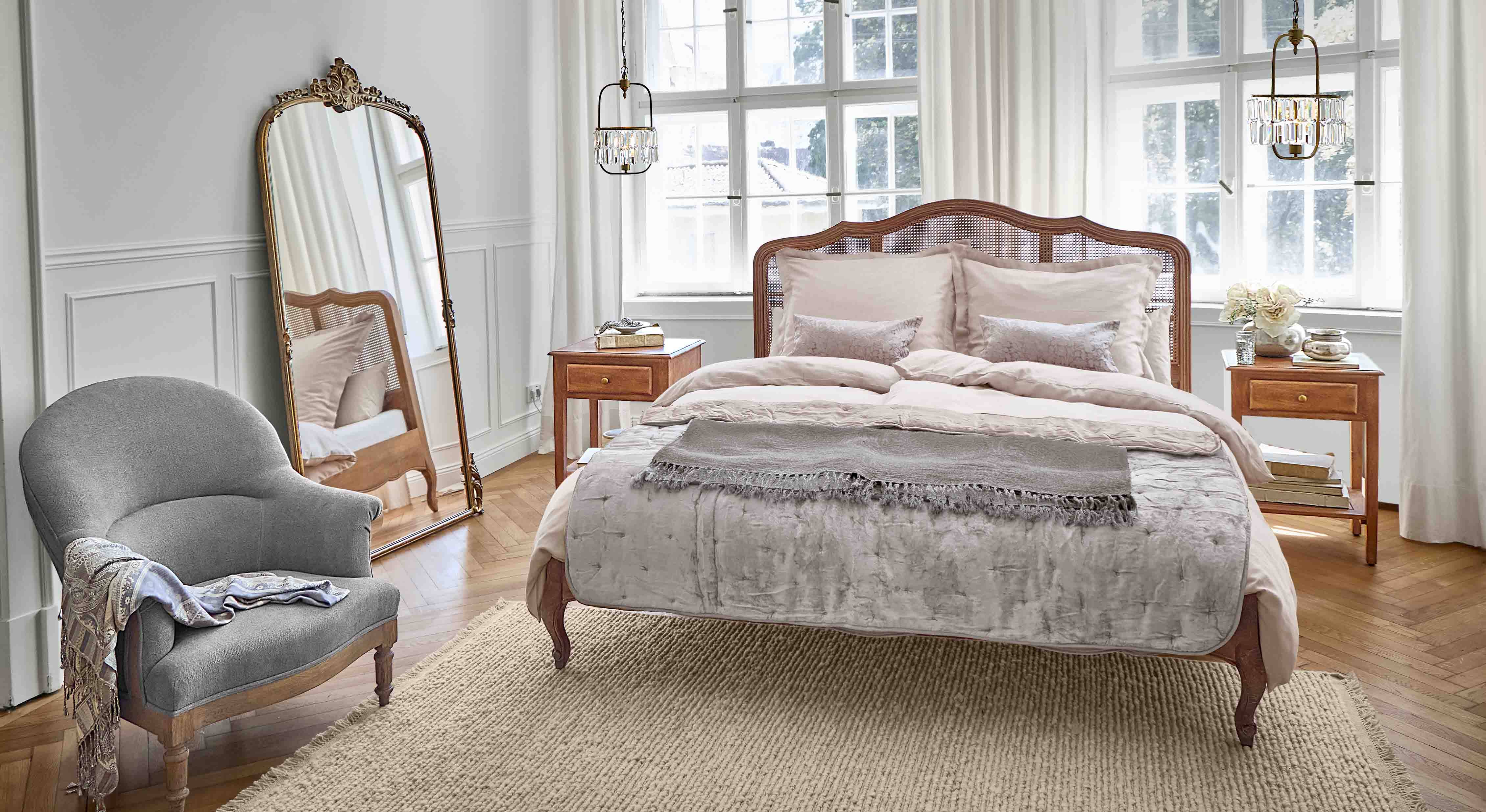 Chambre chaleureuse avec lit en bois et fauteuil gris sur tapis en fibres naturelles