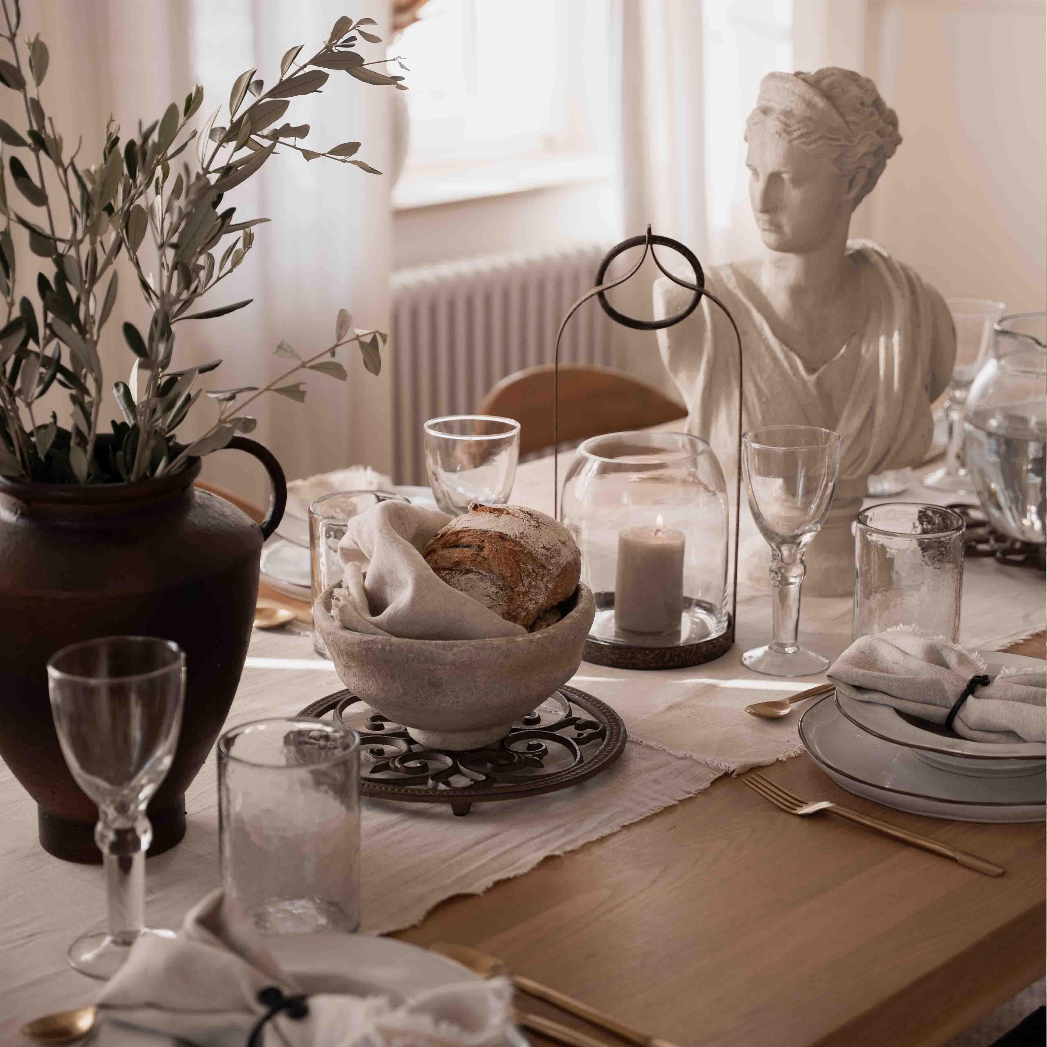 Table décor sobre avec pain, bougie et statue en pierre blanche dans une lumière naturelle douce