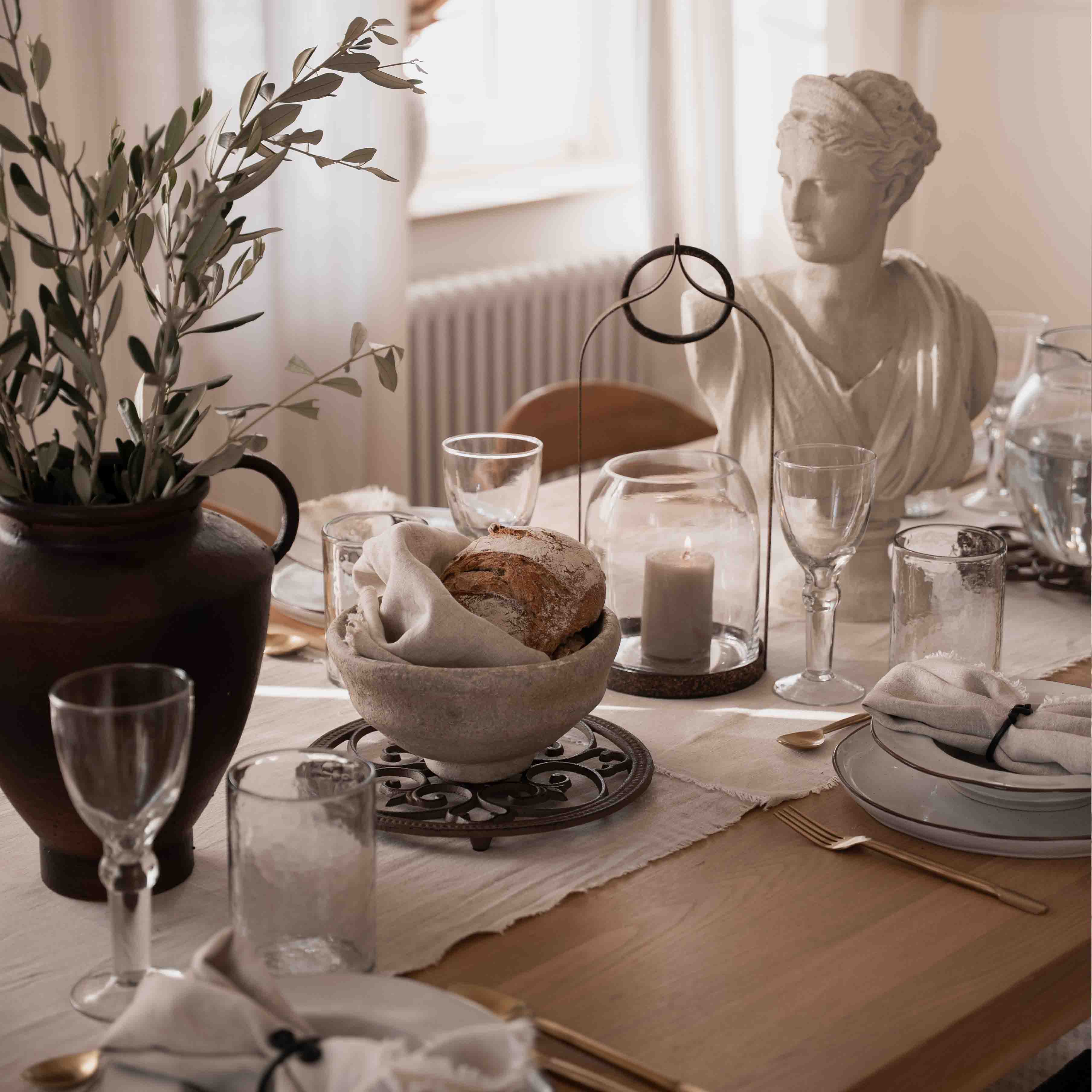 Table décor sobre avec pain, bougie et statue en pierre blanche dans une lumière naturelle douce