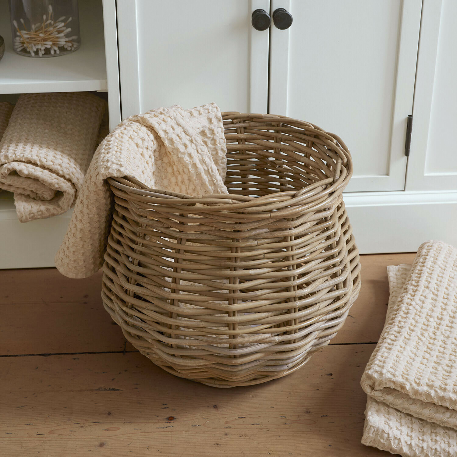 Panier Elvendia Panier en osier naturel avec serviette crème gaufrée posé sur un sol en bois clair