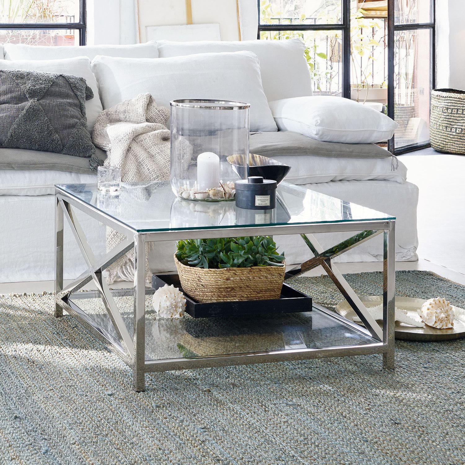 Table basse Stamford Table basse carrée en verre et métal argenté sur tapis dans un salon lumineux