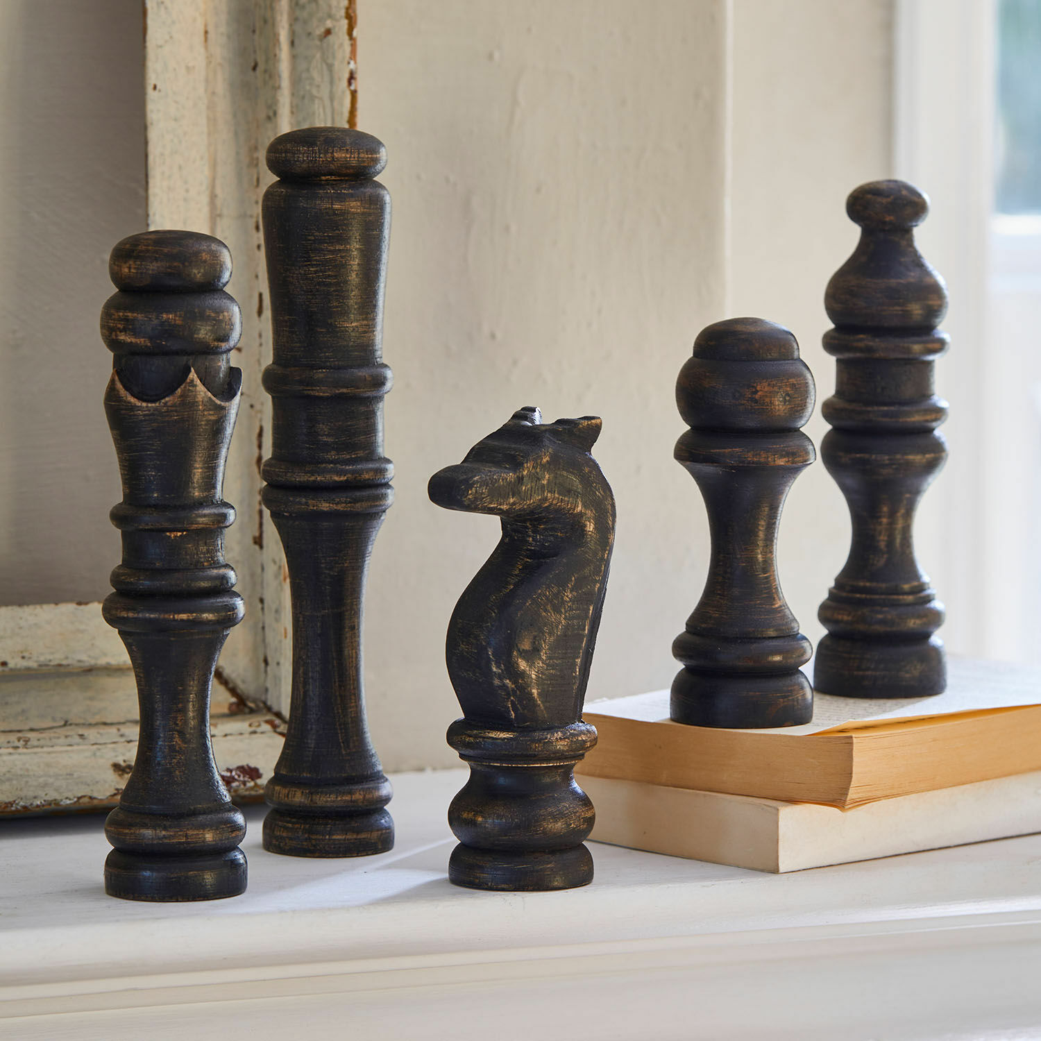 Lot de 5 objets décoratifs Guillemineau Figurines d'échecs décoratives en bois noir vieilli posées sur une étagère près d'un livre.