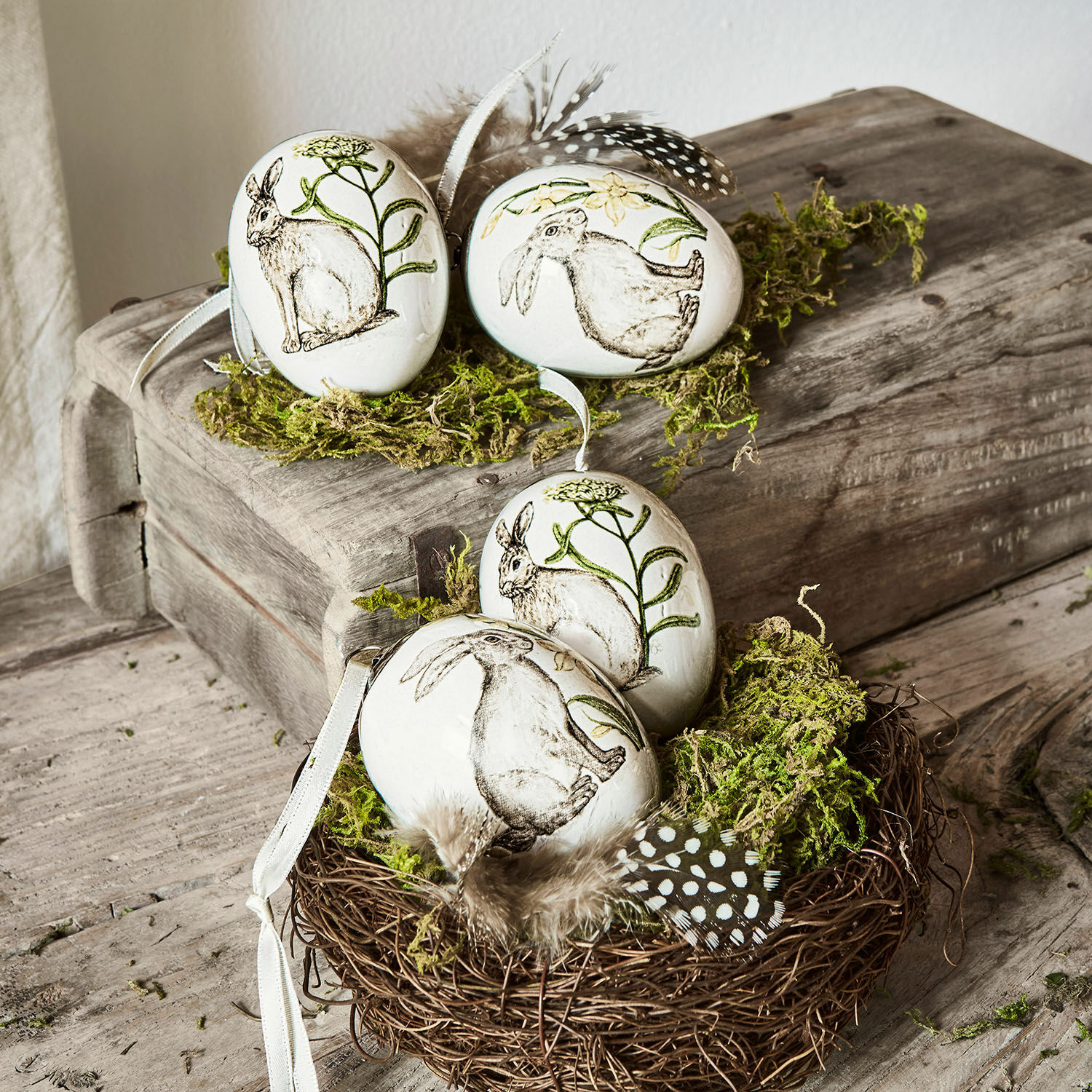 Lot de 4 œufs de Pâques Finna Œufs décoratifs en céramique blanche avec motifs de lapins et plantes, ornés de plumes et de mousse