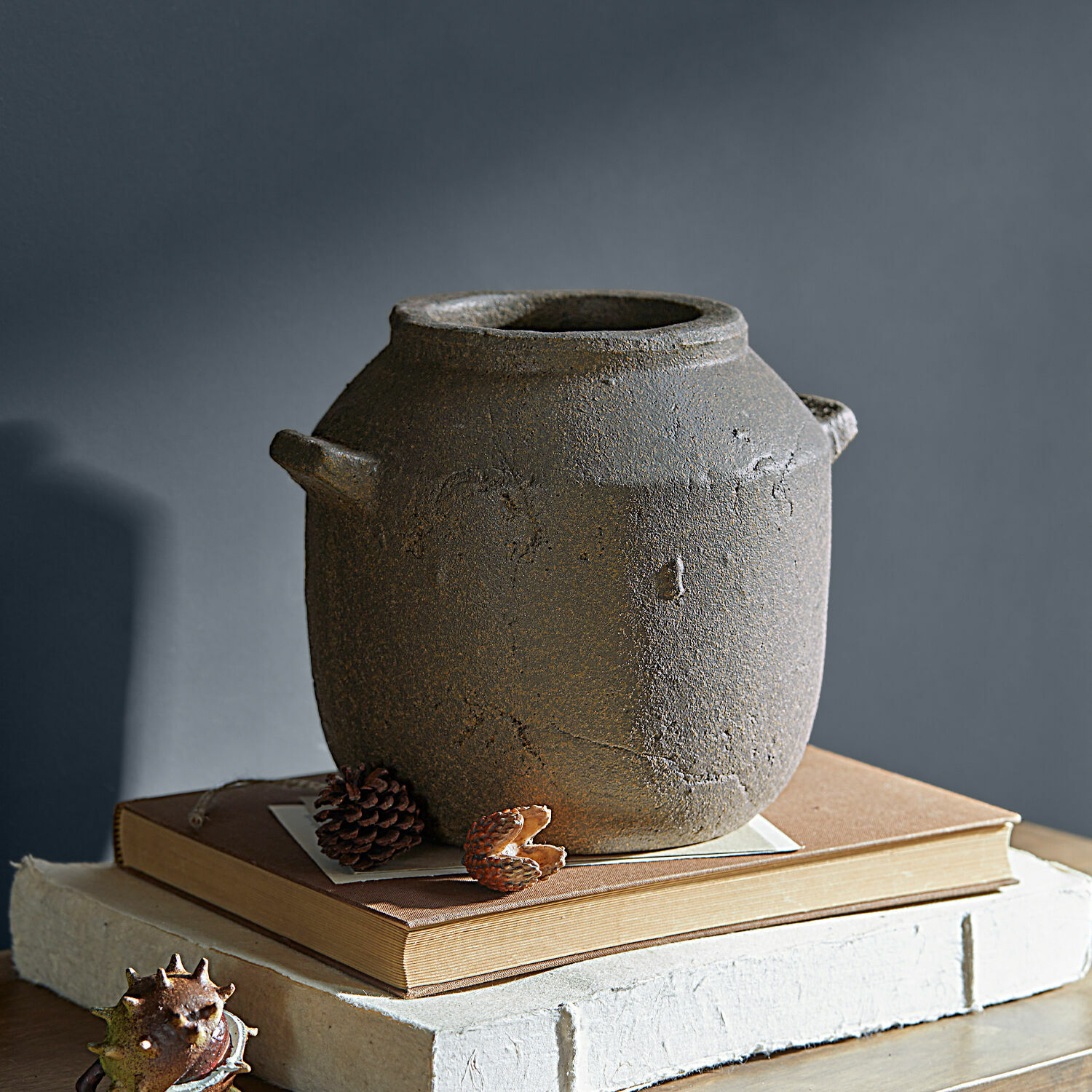 Vase Saintevoux Vase en céramique rustique gris posé sur des livres, décoration intérieure vintage élégante