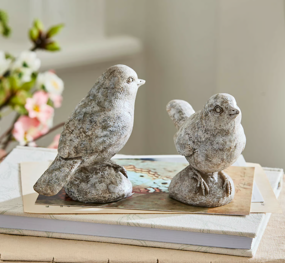 Deux figurines d'oiseaux en pierre grise posées sur des livres, décoration intérieure élégante