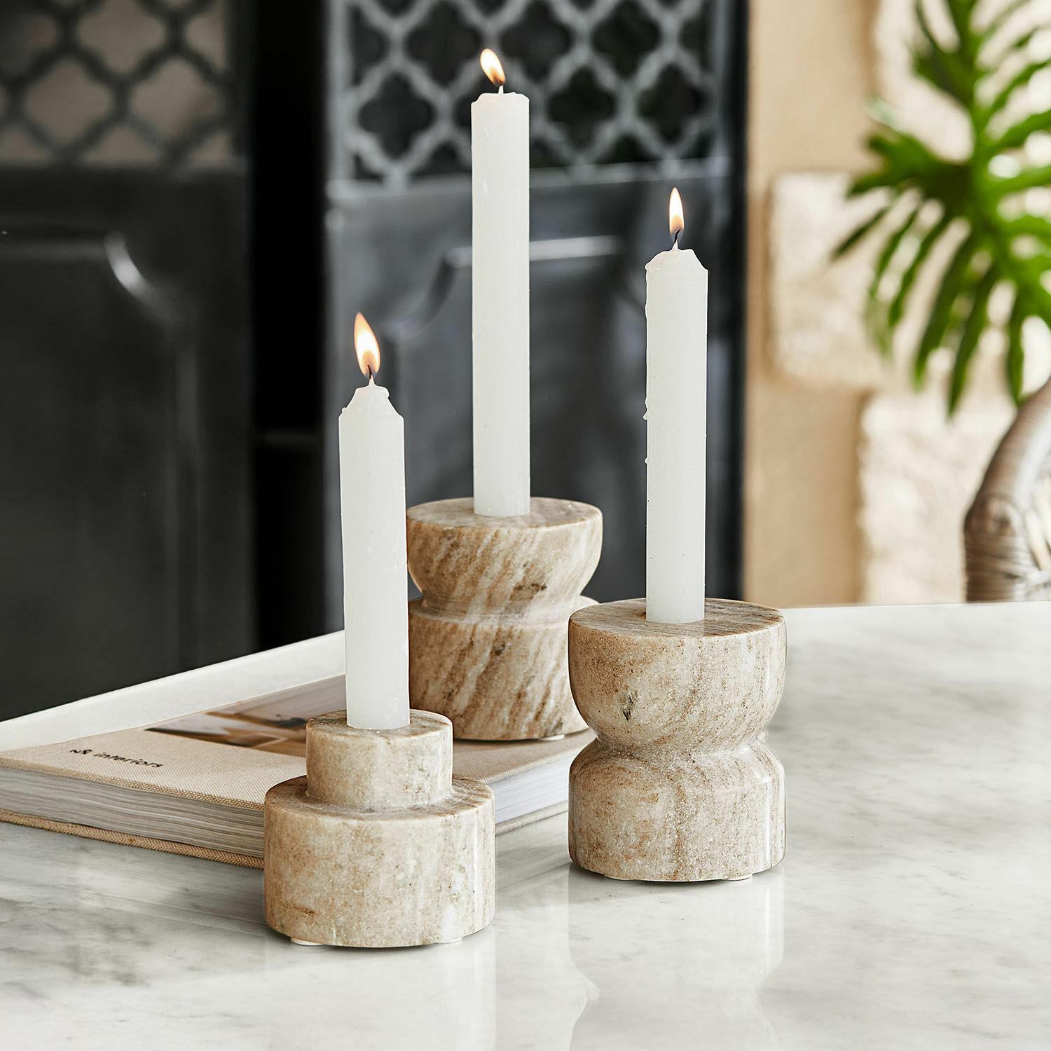Lot de 3 bougeoirs Ulxeno Ensemble de trois bougeoirs en marbre beige avec bougies blanches sur une table en marbre, décoration intérieure