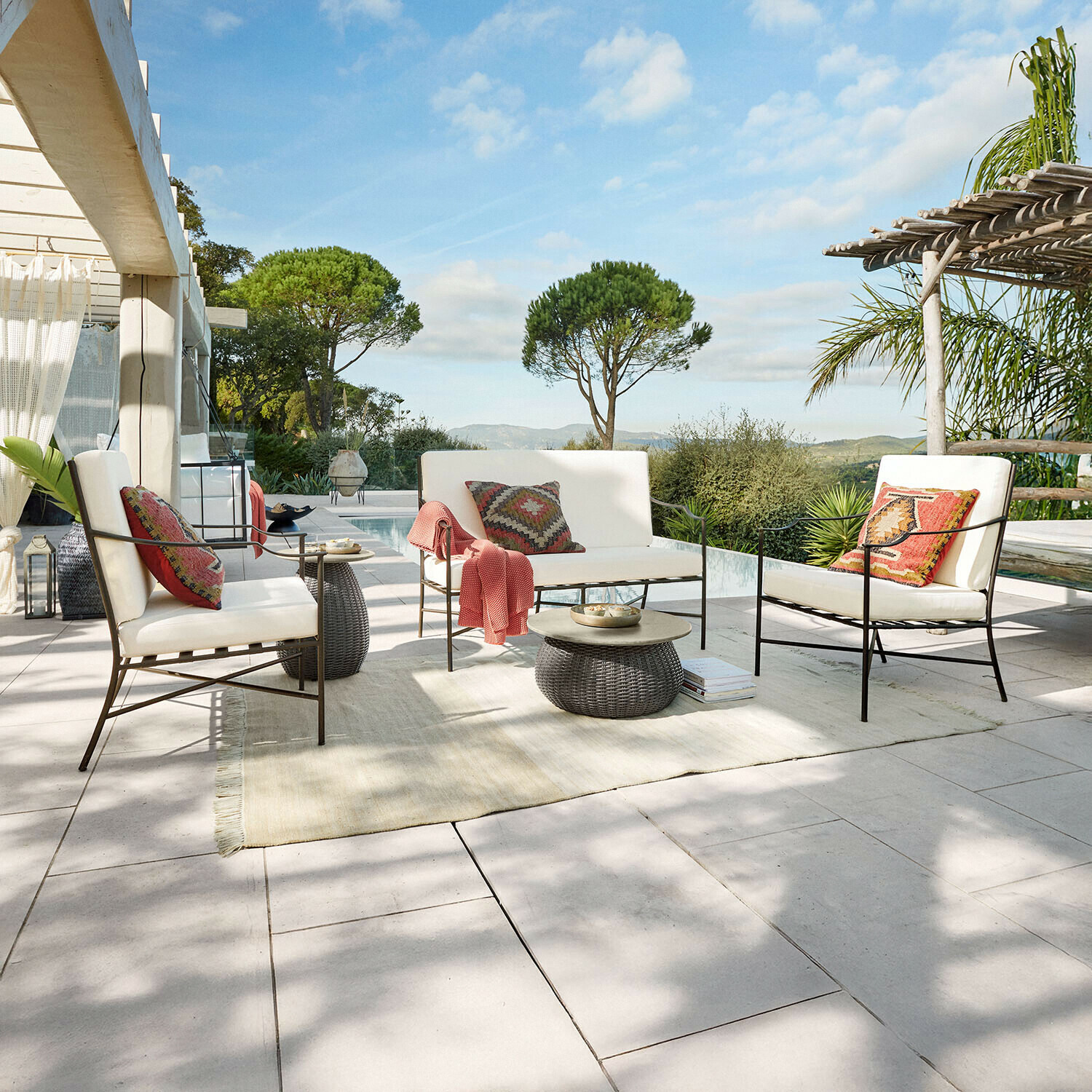 Ensemble de mobilier de jardin en métal avec coussins crème sur terrasse avec vue sur piscine