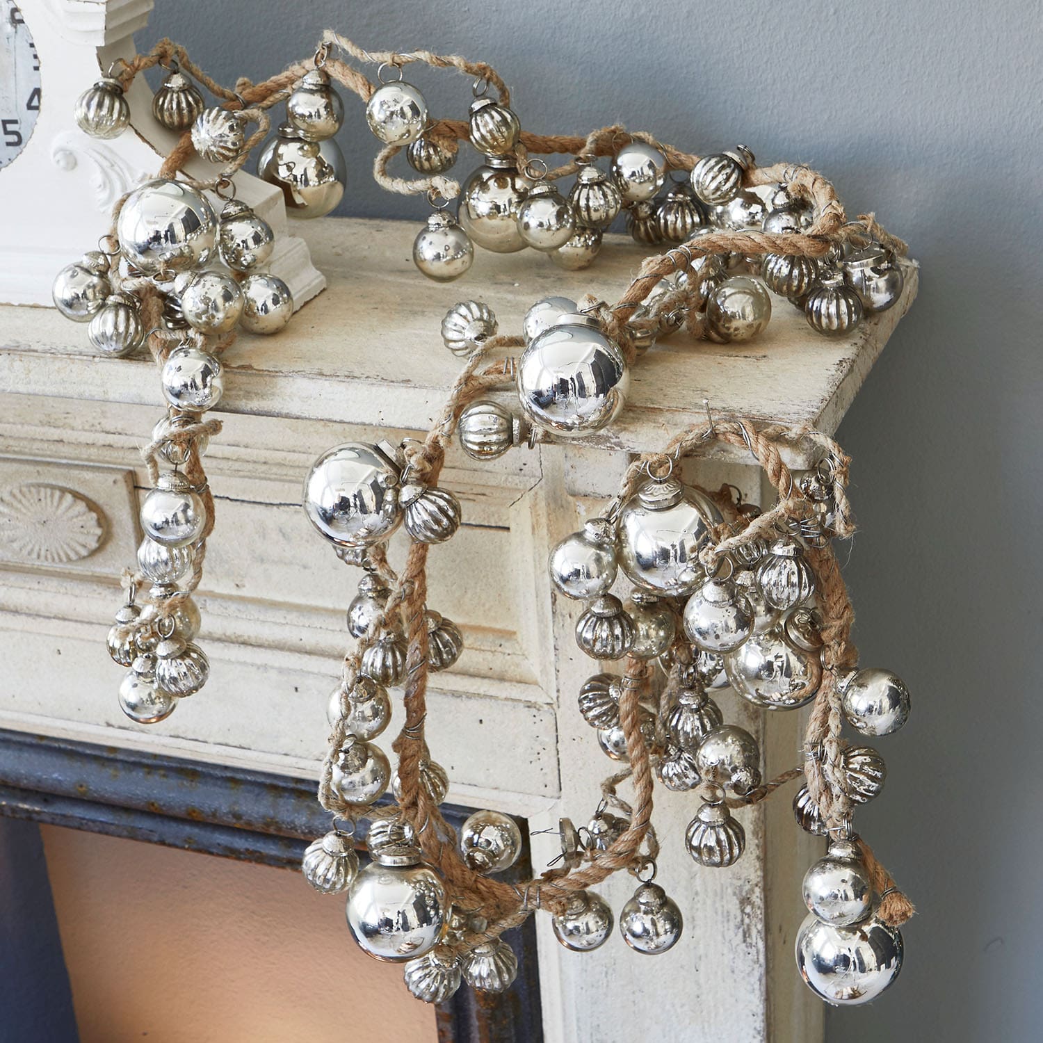 Guirlande en corde de jute avec boules décoratives métalliques argentées posée sur une cheminée