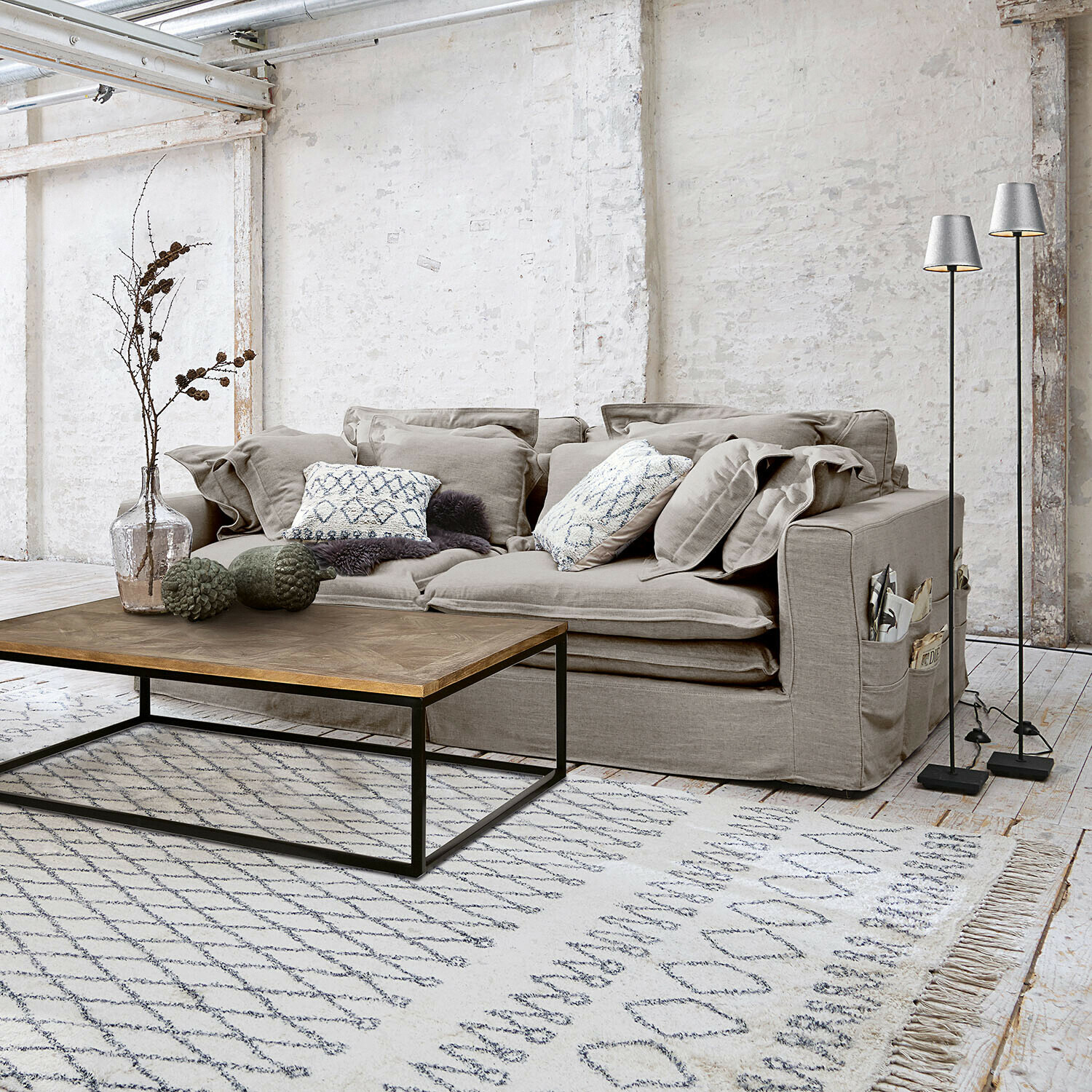 Canapé Terell Canapé gris en tissu avec coussins et table basse en bois sur tapis clair dans un salon moderne