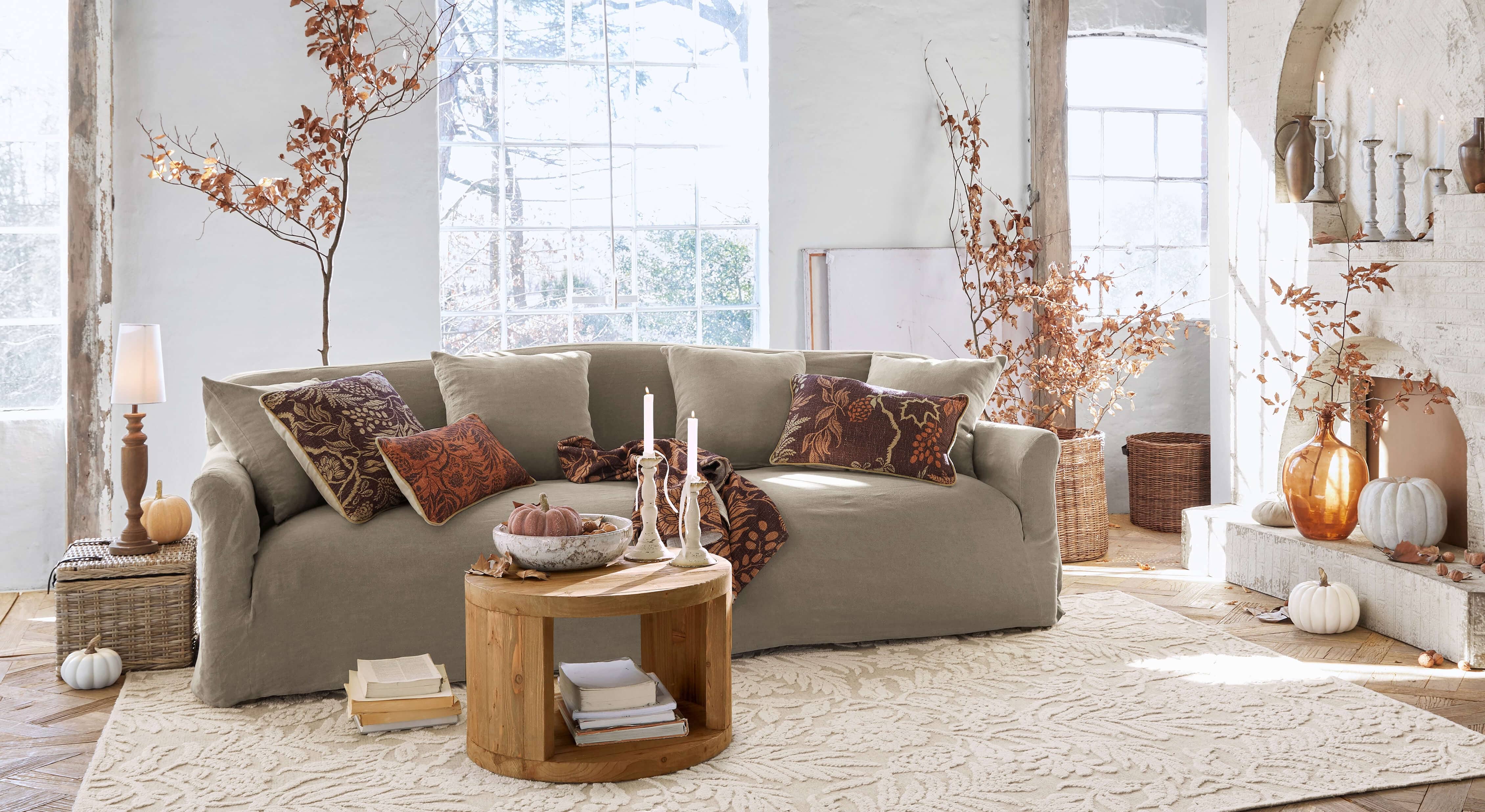 Canapé beige en tissu dans un salon chaleureux décoré pour l'automne avec table basse en bois