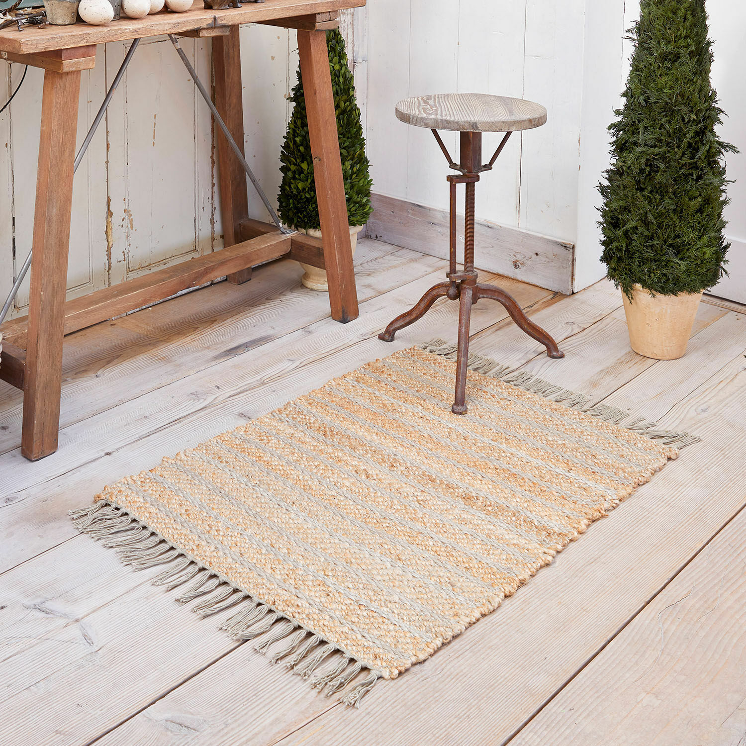 Tapis Voyage Tapis en jute beige et gris à rayures avec franges sur un sol en bois clair, décoration intérieure