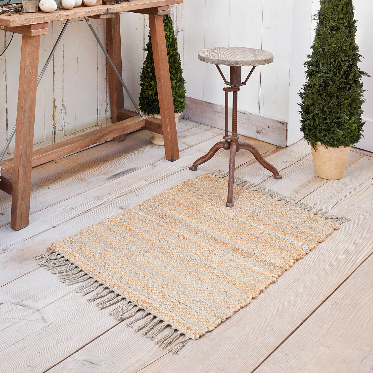 Tapis Voyage Tapis en jute beige et gris à rayures avec franges sur un sol en bois clair, décoration intérieure