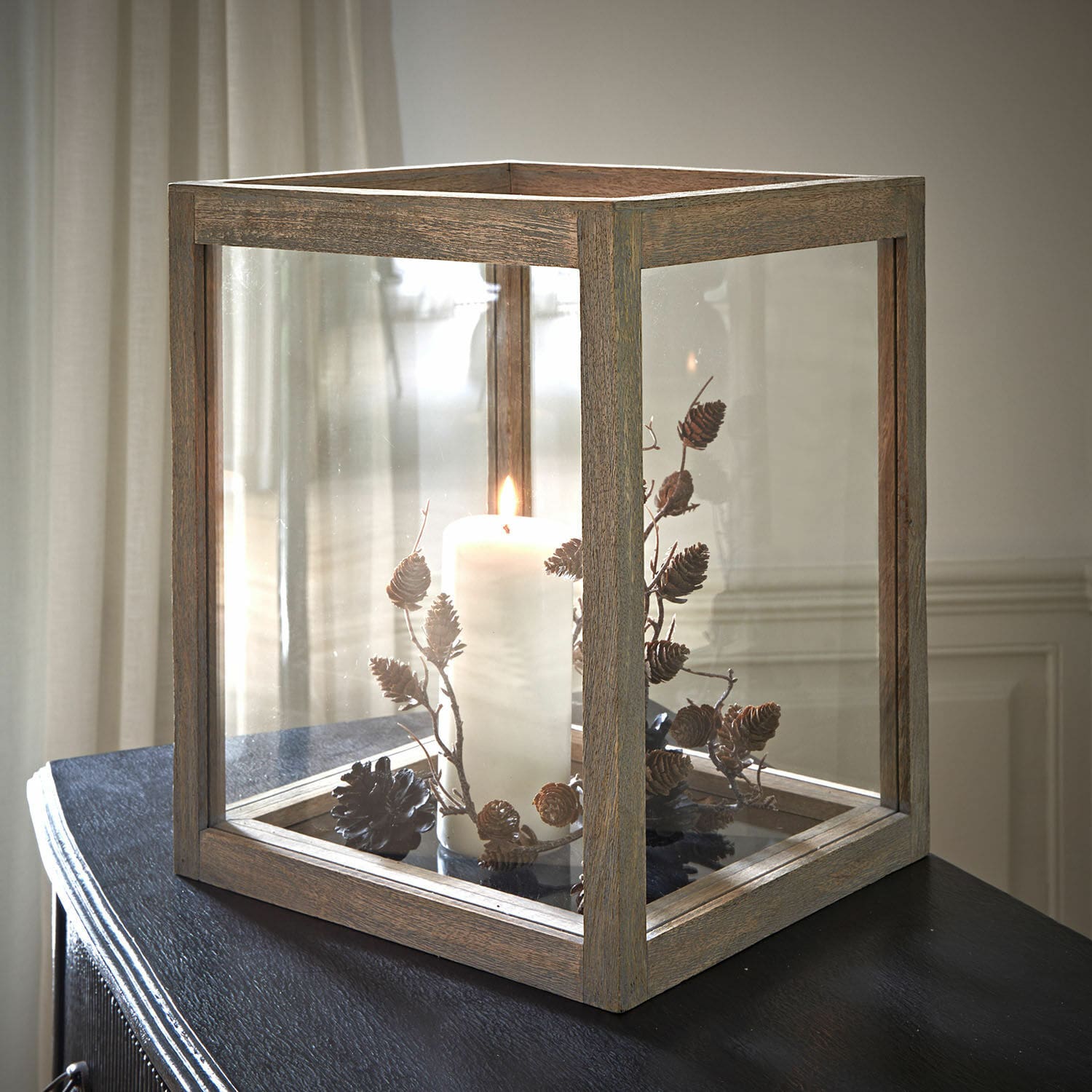 Photophore Solvik Lanterne en bois avec verre transparent et bougie blanche décorée de pommes de pin sur surface noire