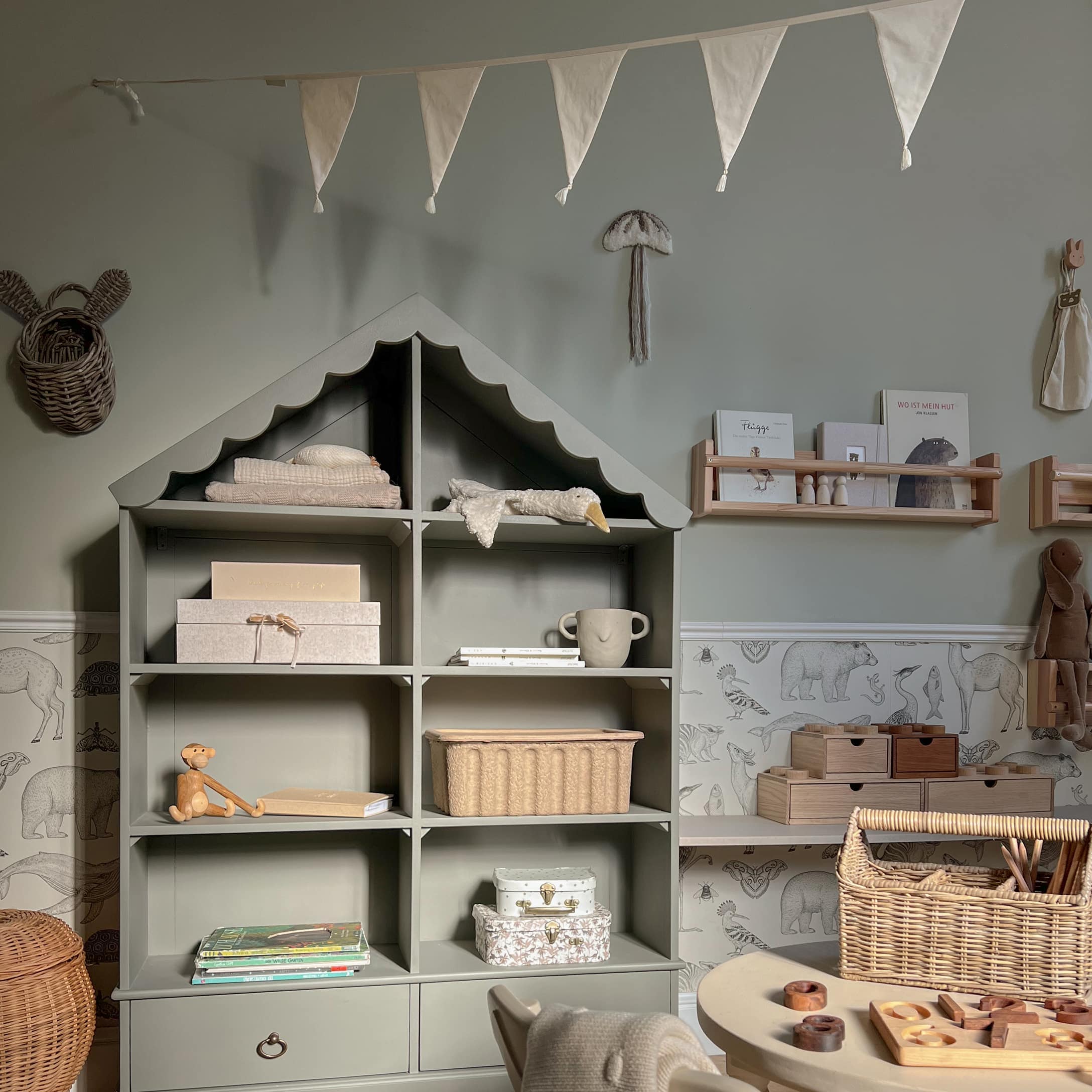 Étagère grise en bois en forme de maison avec décorations et jouets dans une chambre d'enfant