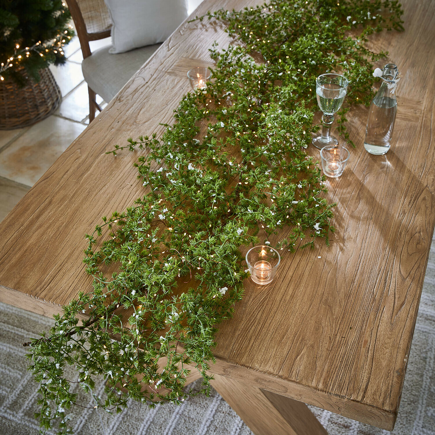 Guirlande LED Kalitha Table en bois décorée de branches vertes et bougies, ambiance naturelle et festive