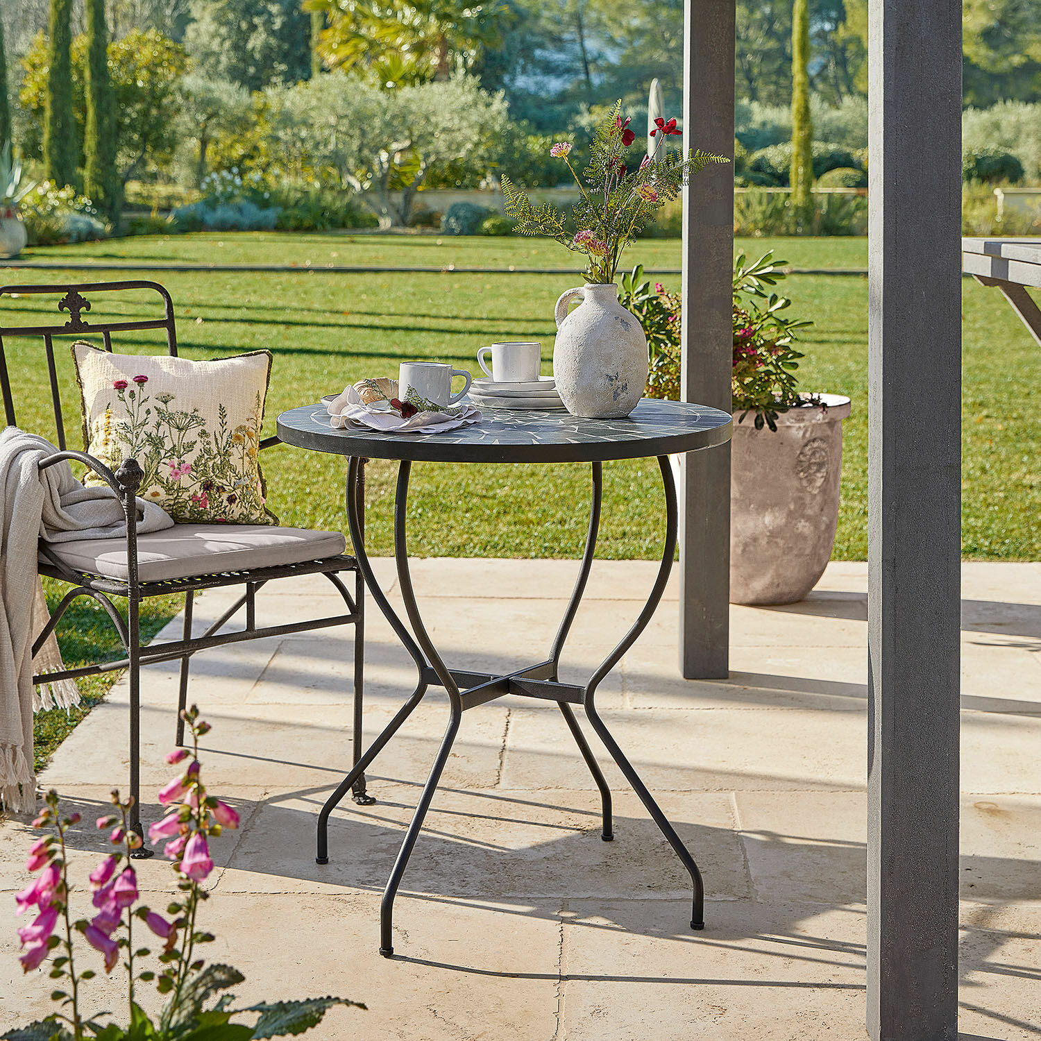 Table Ballaigues Table de jardin ronde avec cadre en métal et plateau en mosaïque gris sur terrasse ensoleillée