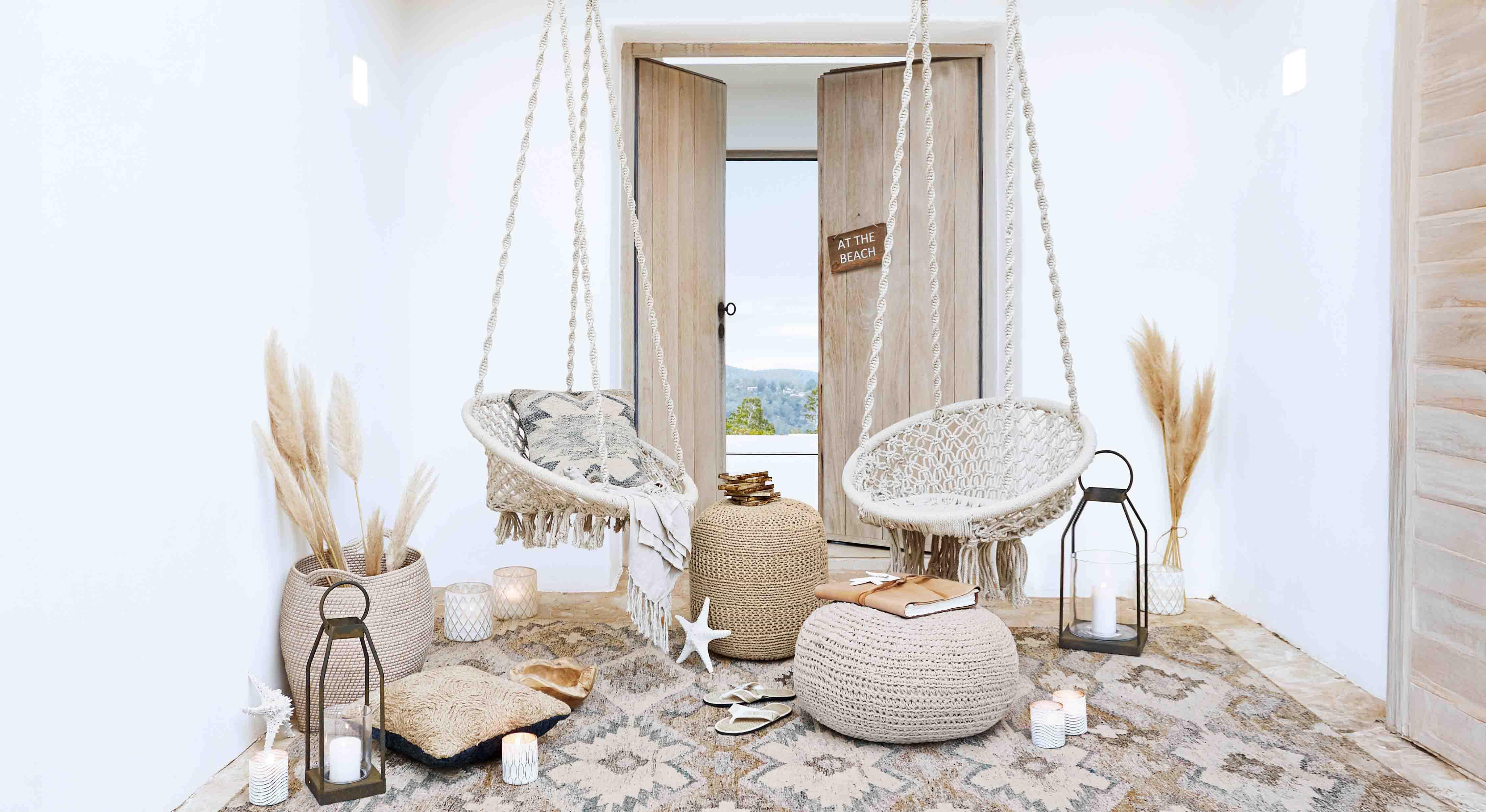 Salon cosy avec fauteuils suspendus en macramé blanc et décorations naturelles style bohème